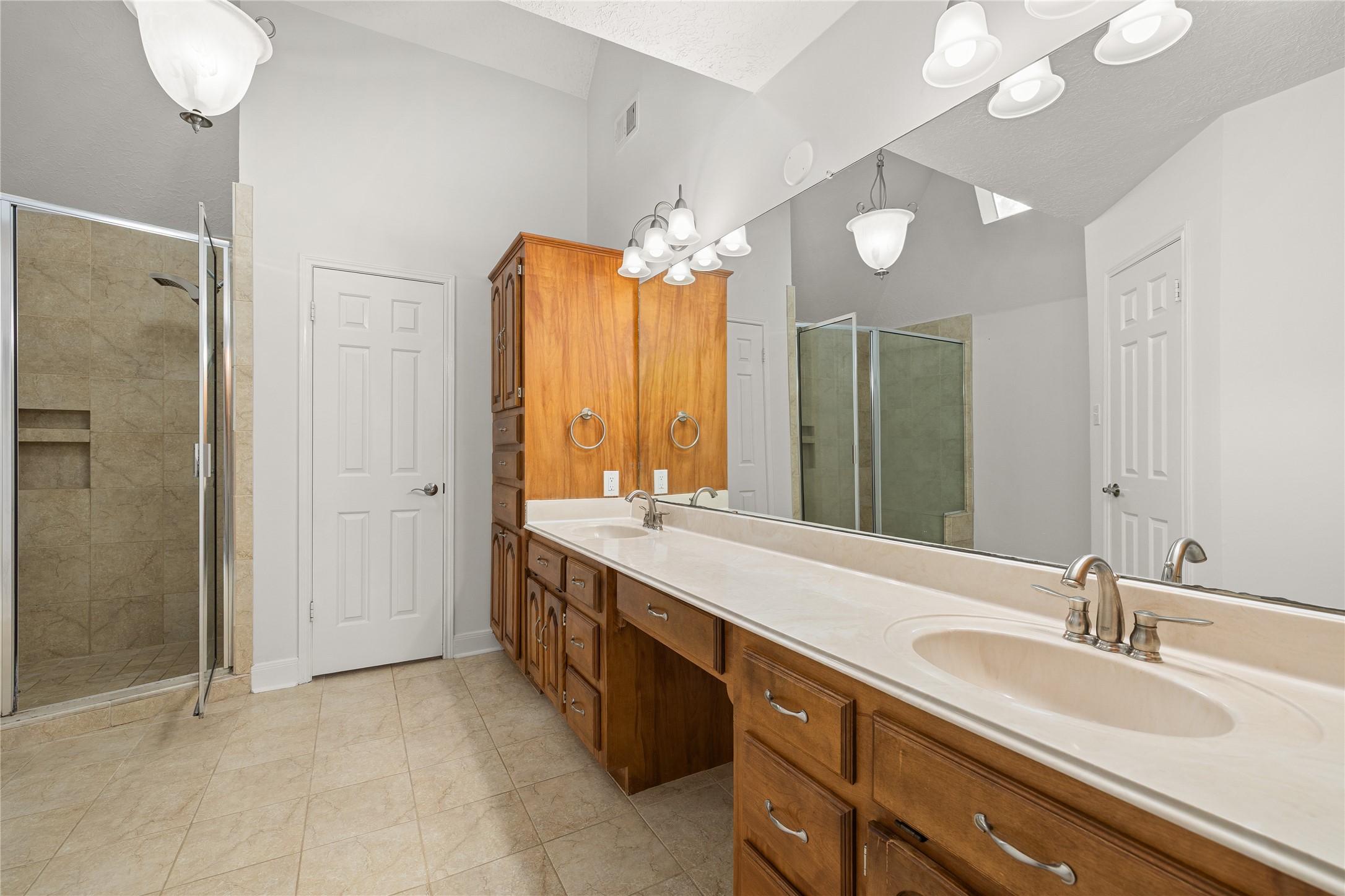 This additional perspective reveals the impressive scale of the primary bath, highlighting its soaring ceilings and premium amenities. The space is anchored by a glass-enclosed walk-in shower and a sprawling vanity, creating a luxurious and functional ensuite experience.