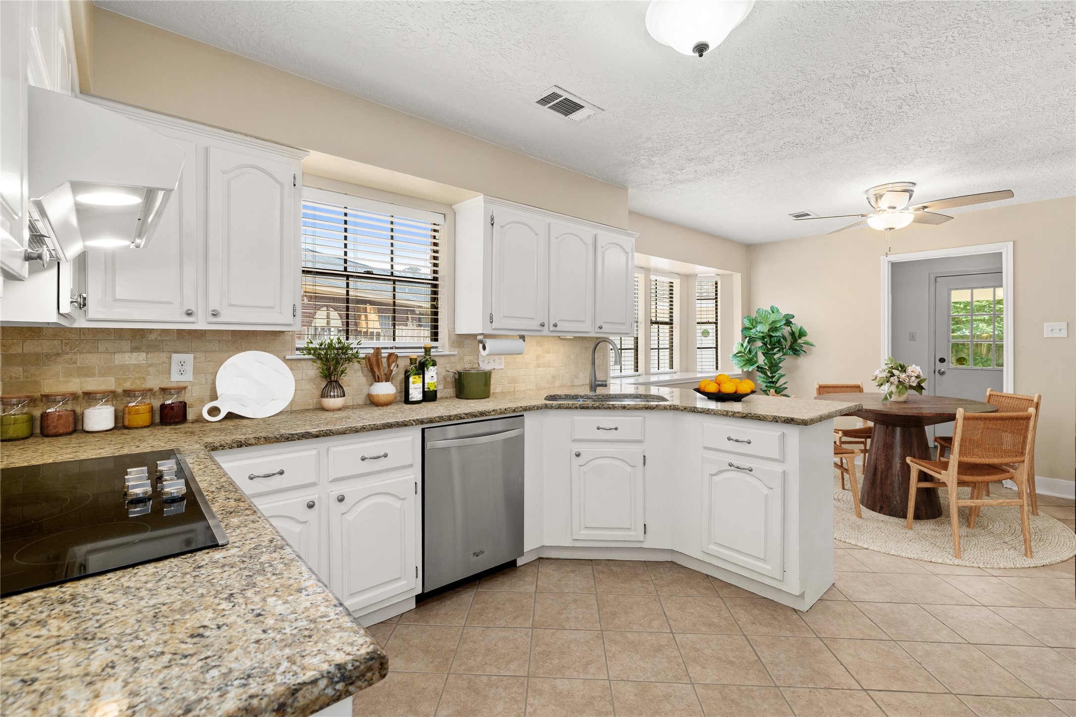 This bright and functional kitchen is a chefs delight, combining timeless style with a layout designed for effortless entertaining. Crisp white cabinetry is beautifully complemented by granite countertops and a stone-tile backsplash, creating an inviting space that flows seamlessly into the sun-lit breakfast nook. *Virtually Staged