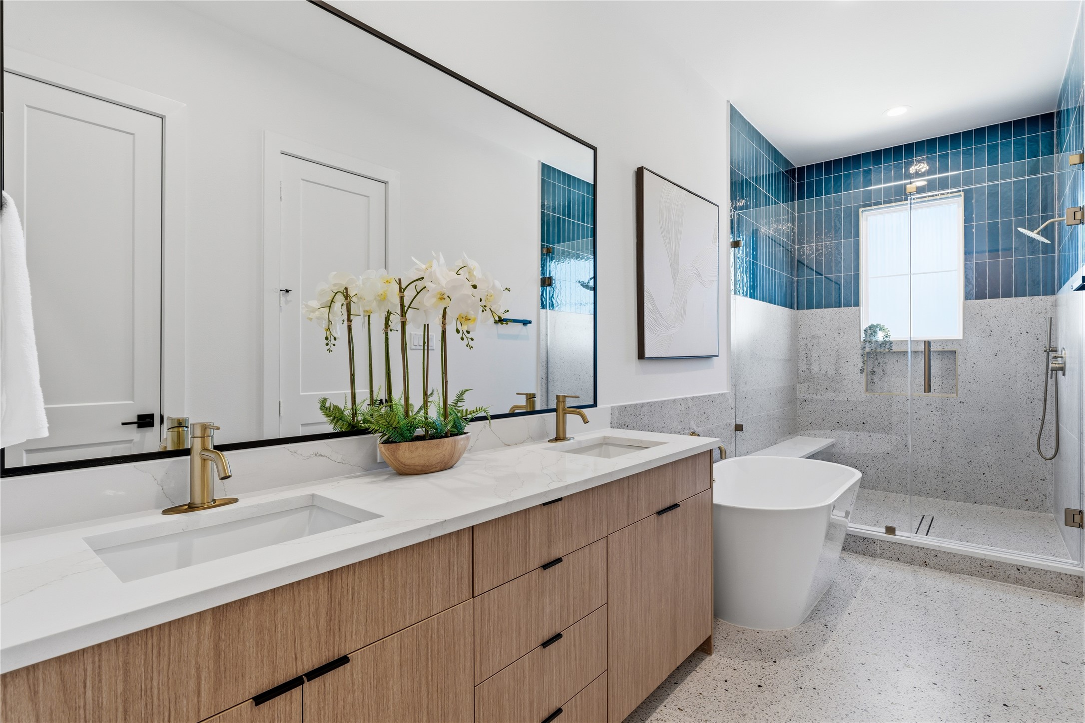 Spa-like primary bathroom with dual vanities, freestanding tub, and walk-in glass shower.