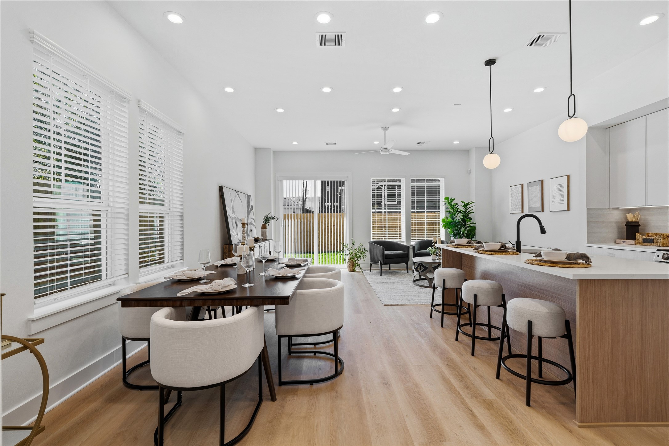 The expansive layout is defined by high ceilings, recessed lighting, and warm vinyl plank floors. Large windows and glass doors ensure the voluminous space is saturated with natural light.