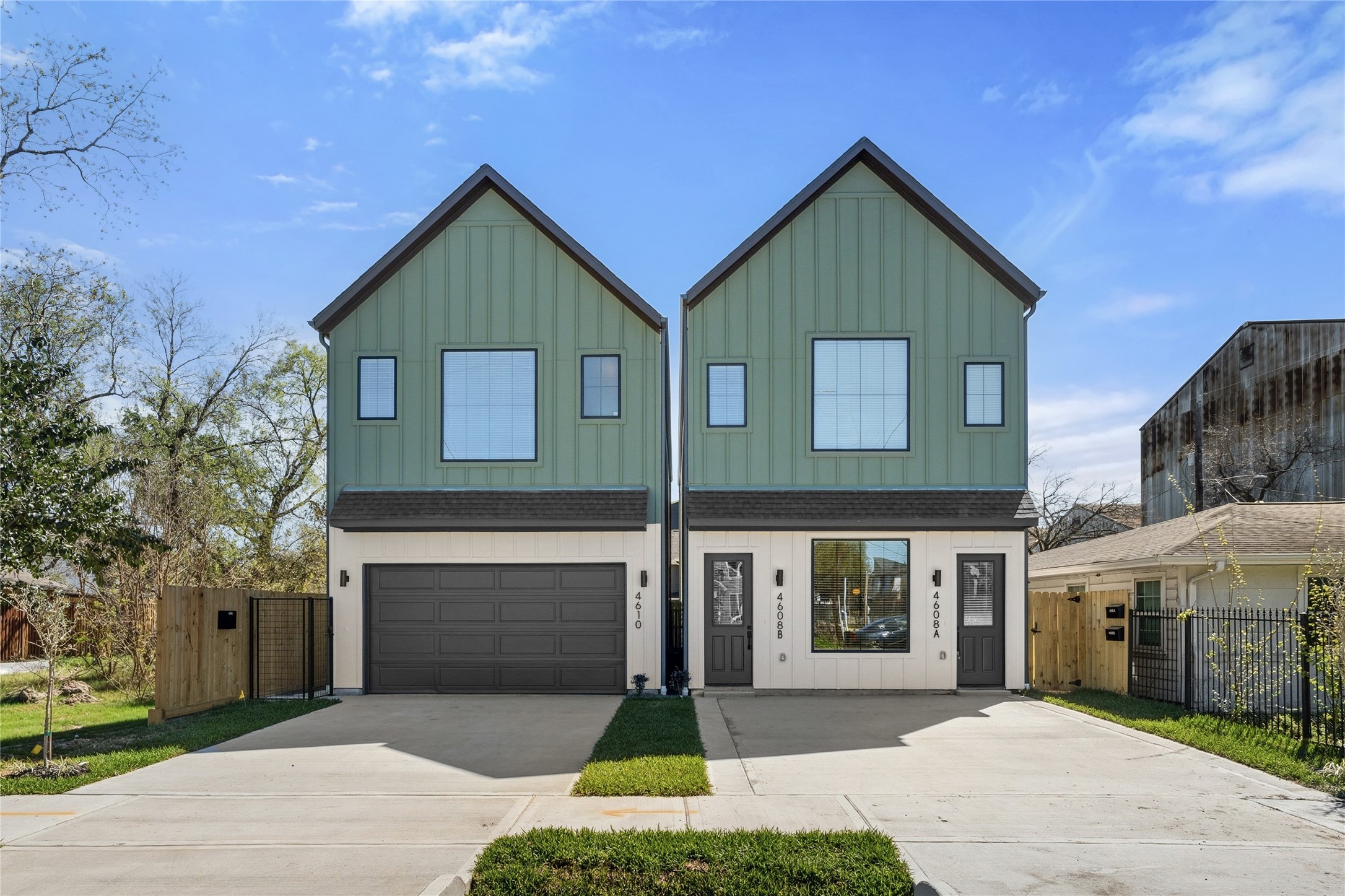 This modern two-story triplex features a crisp white facade contrasted by a bold black garage door and clean architectural lines.