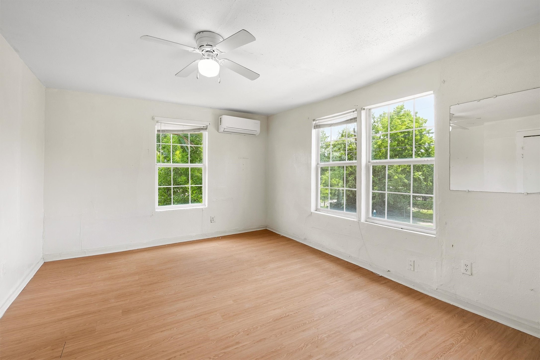 This inviting bedroom features laminate flooring, a ceiling fan, and windows with privacy blinds, creating a comfortable and relaxing retreat with a bright, polished feel.