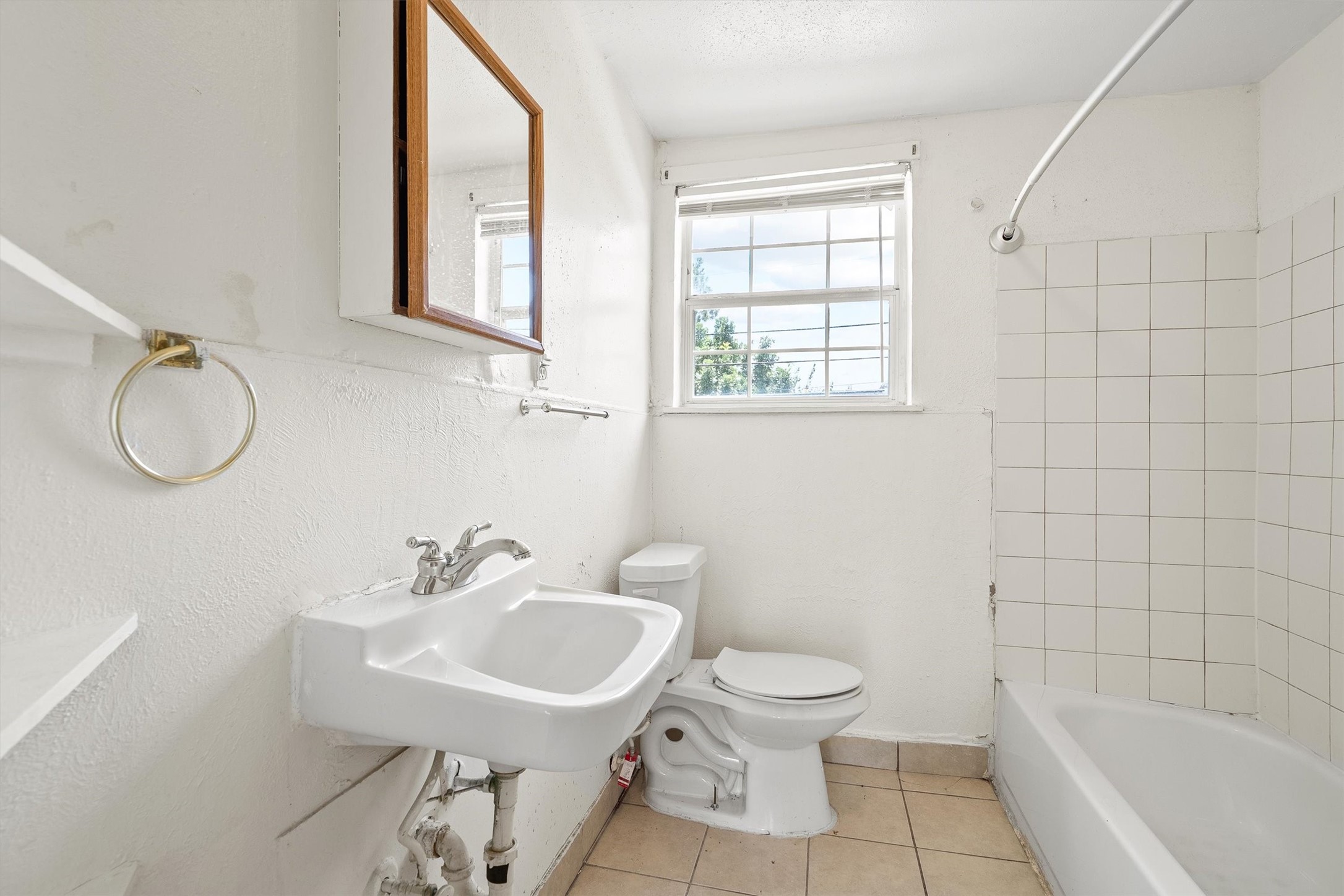 This bathroom features a pedestal sink, a toilet, and a shower/tub combo, offering a clean, functional design with everyday comfort in mind.