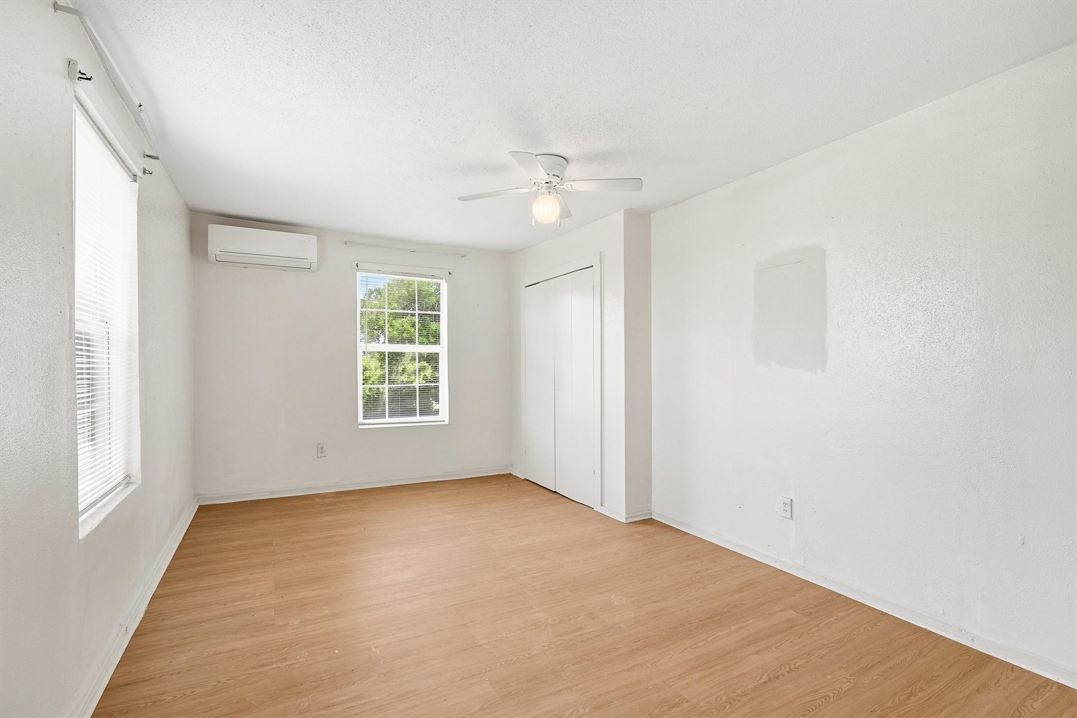 The second bedroom offers a comfortable and inviting retreat with laminate flooring, a ceiling fan, and windows with privacy blinds, blending style, comfort, and functionality.