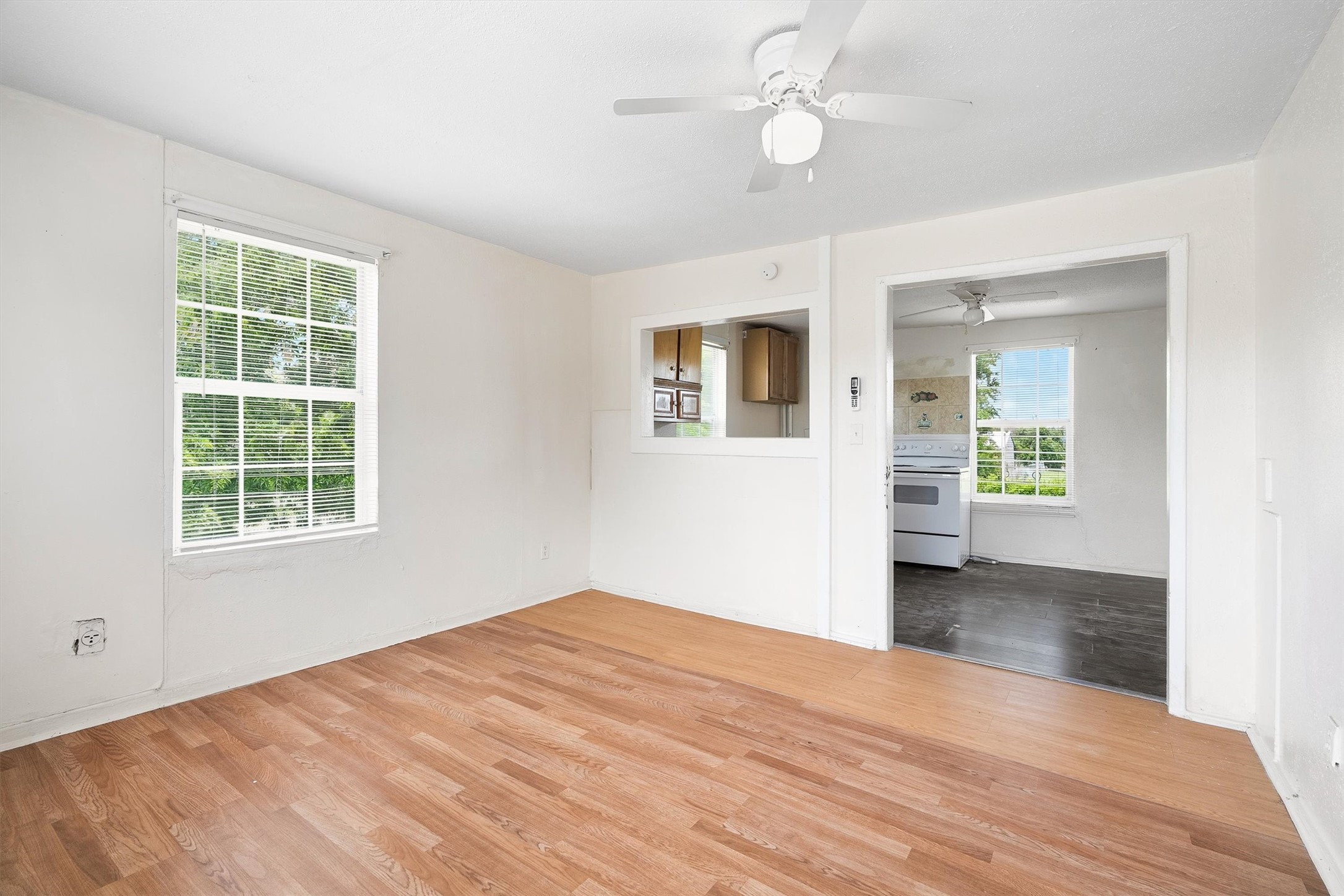The living room offers a comfortable and welcoming space with laminate flooring, a ceiling fan, and windows with privacy blinds, creating the perfect setting for relaxing and entertaining.