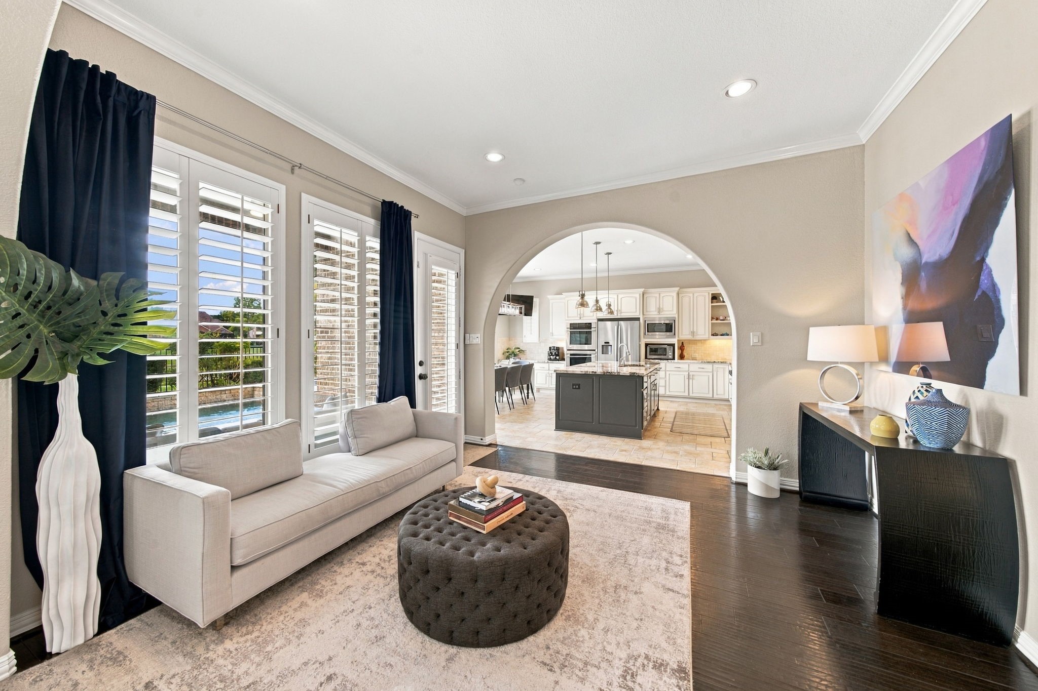 This light-filled sitting area offers an open connection to the kitchen through an arched entry, providing flexible additional seating and entertaining space.