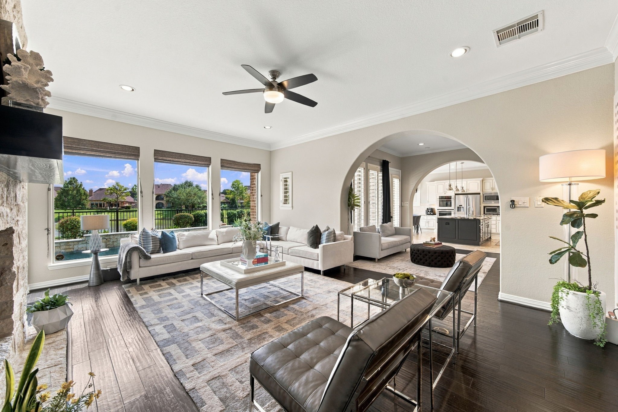 The spacious living area combines multiple seating zones, abundant natural light and views of the pool and lake beyond.