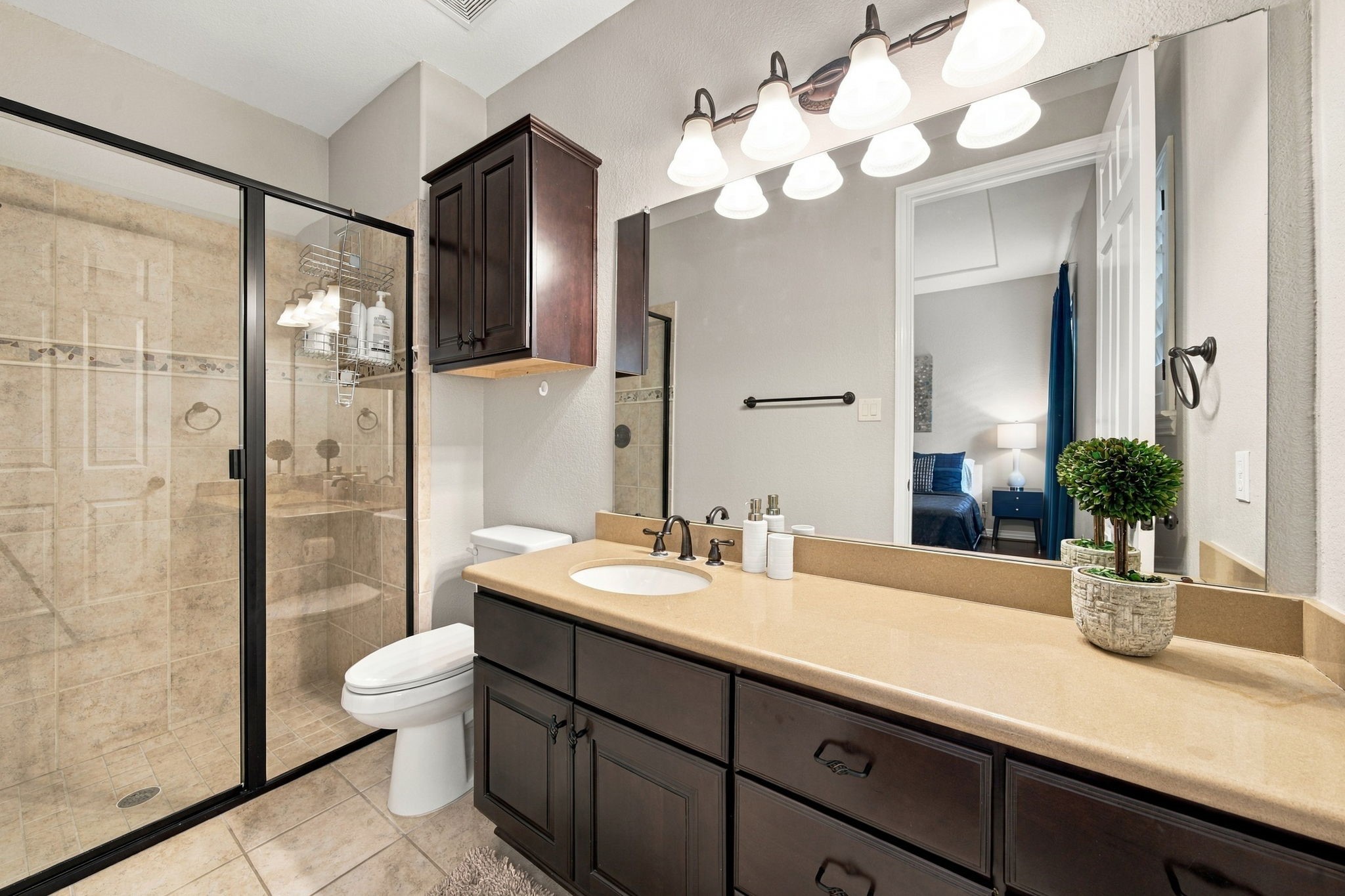 The en-suite bathroom includes an extended vanity, ample storage and a glass-enclosed standing shower.