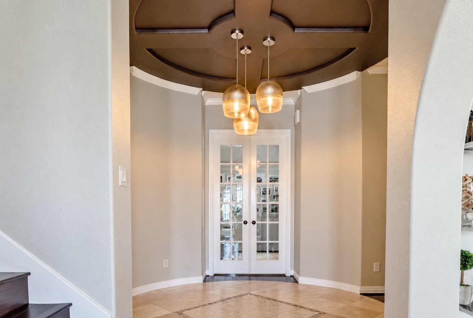 The entry foyer makes a distinctive first impression with an architectural ceiling treatment and clustered pendant lighting