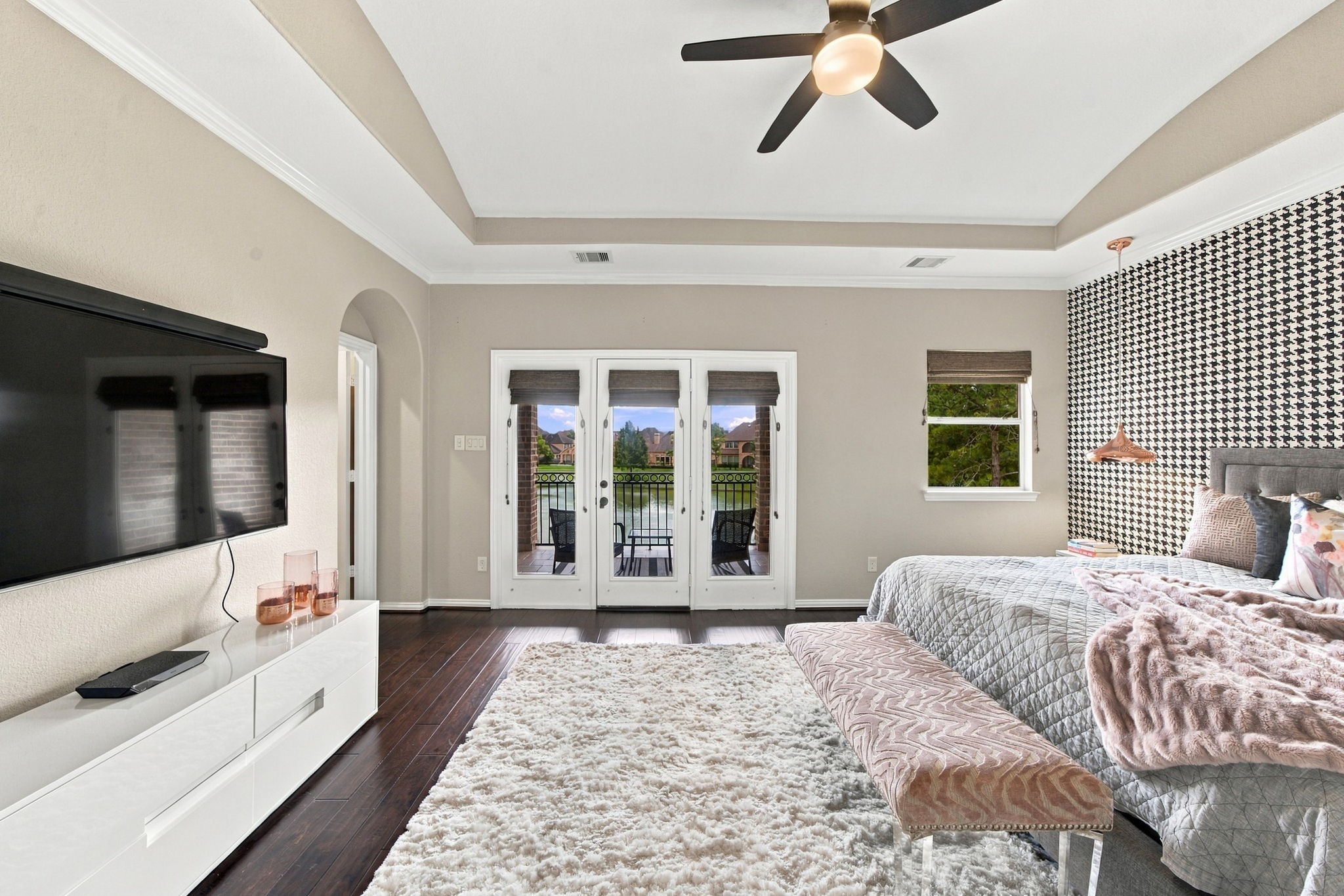 French doors connect the spacious primary bedroom to a private covered balcony with serene lake views.