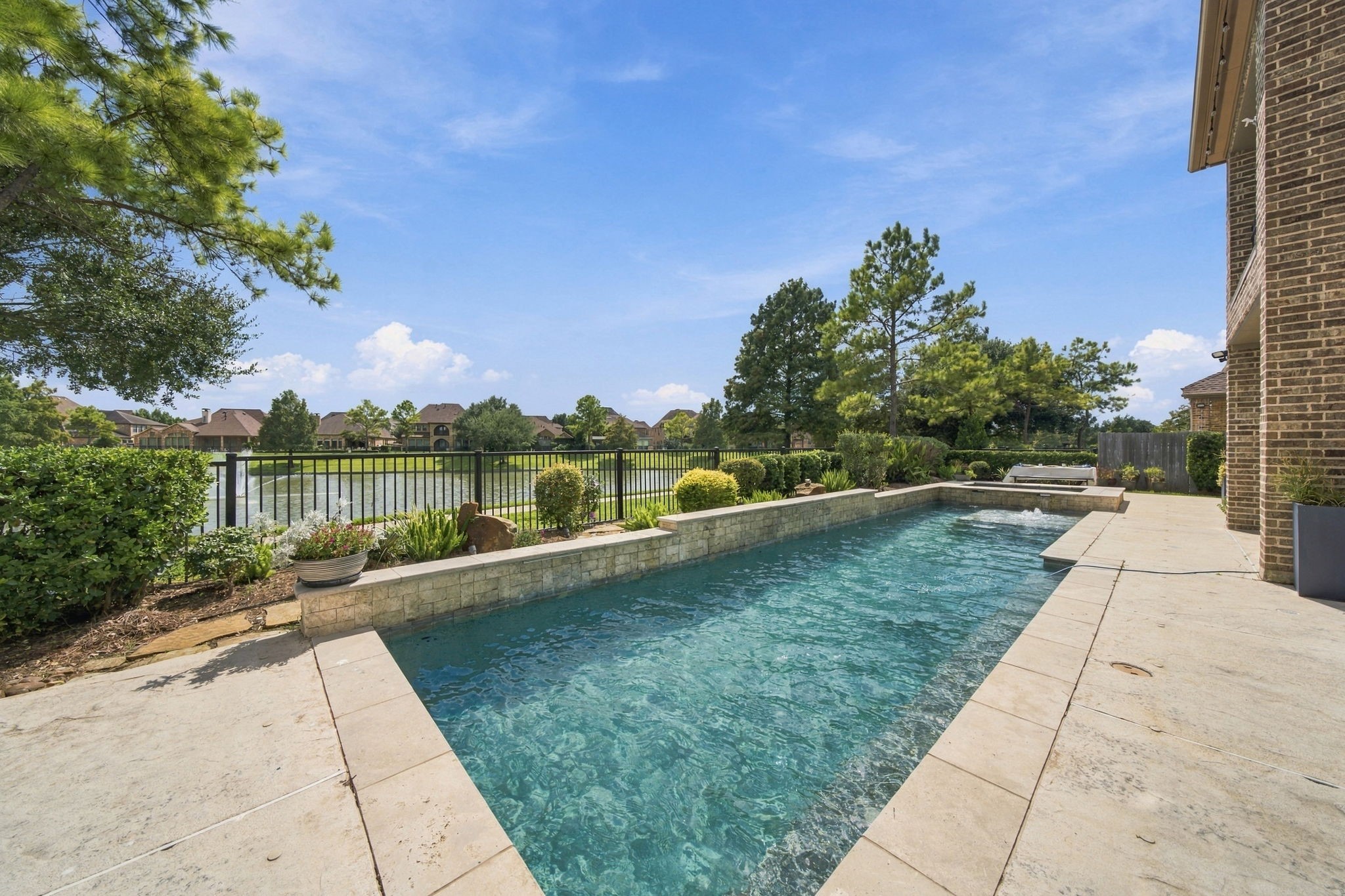 The pool and raised spa overlook the neighborhood lake, creating a scenic backdrop for outdoor living.