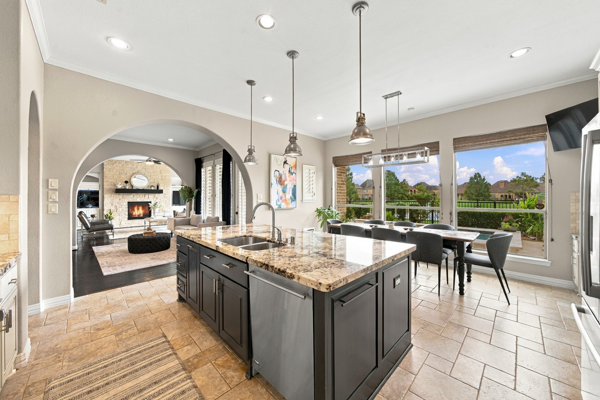 The open kitchen centers around a generous granite island with ample storage, stainless-steel appliances and seamless flow to the dining and living spaces.