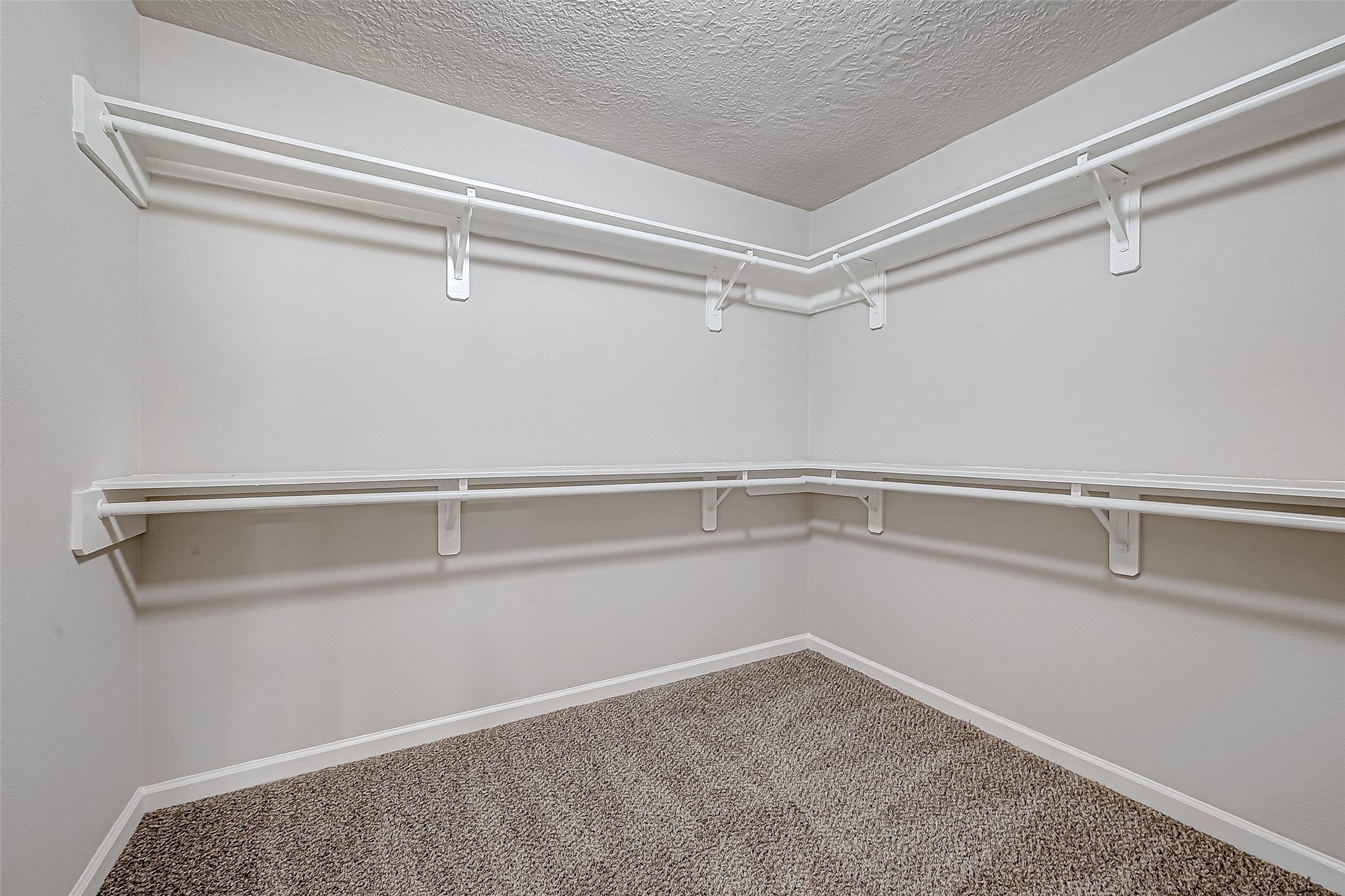 Walk-in closet featuring dual-level white shelving perfect for organizing clothing and accessories.