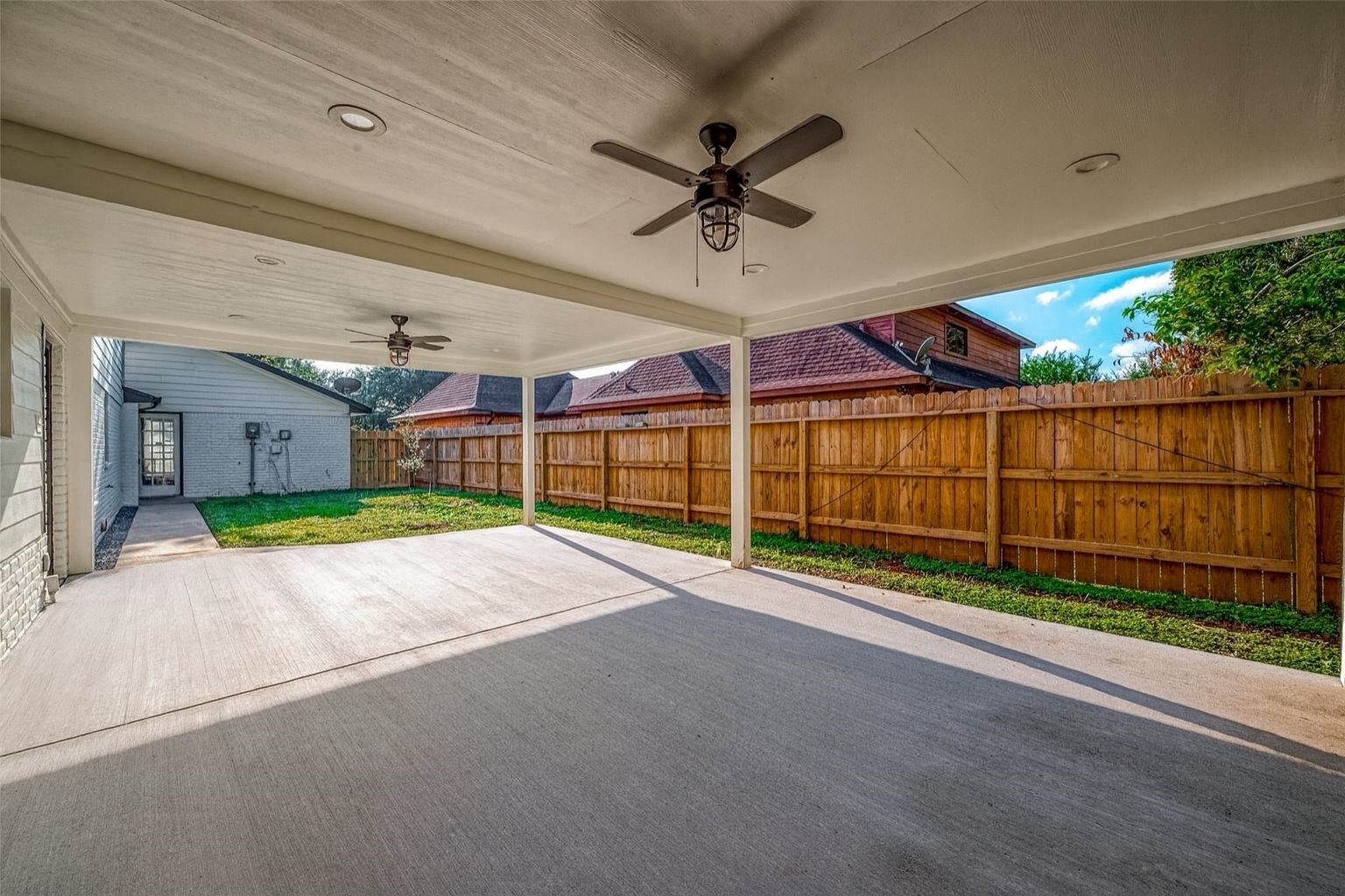 A covered patio with ceiling fans offers an ideal setting for outdoor gatherings, while the fenced yard ensures privacy and security.