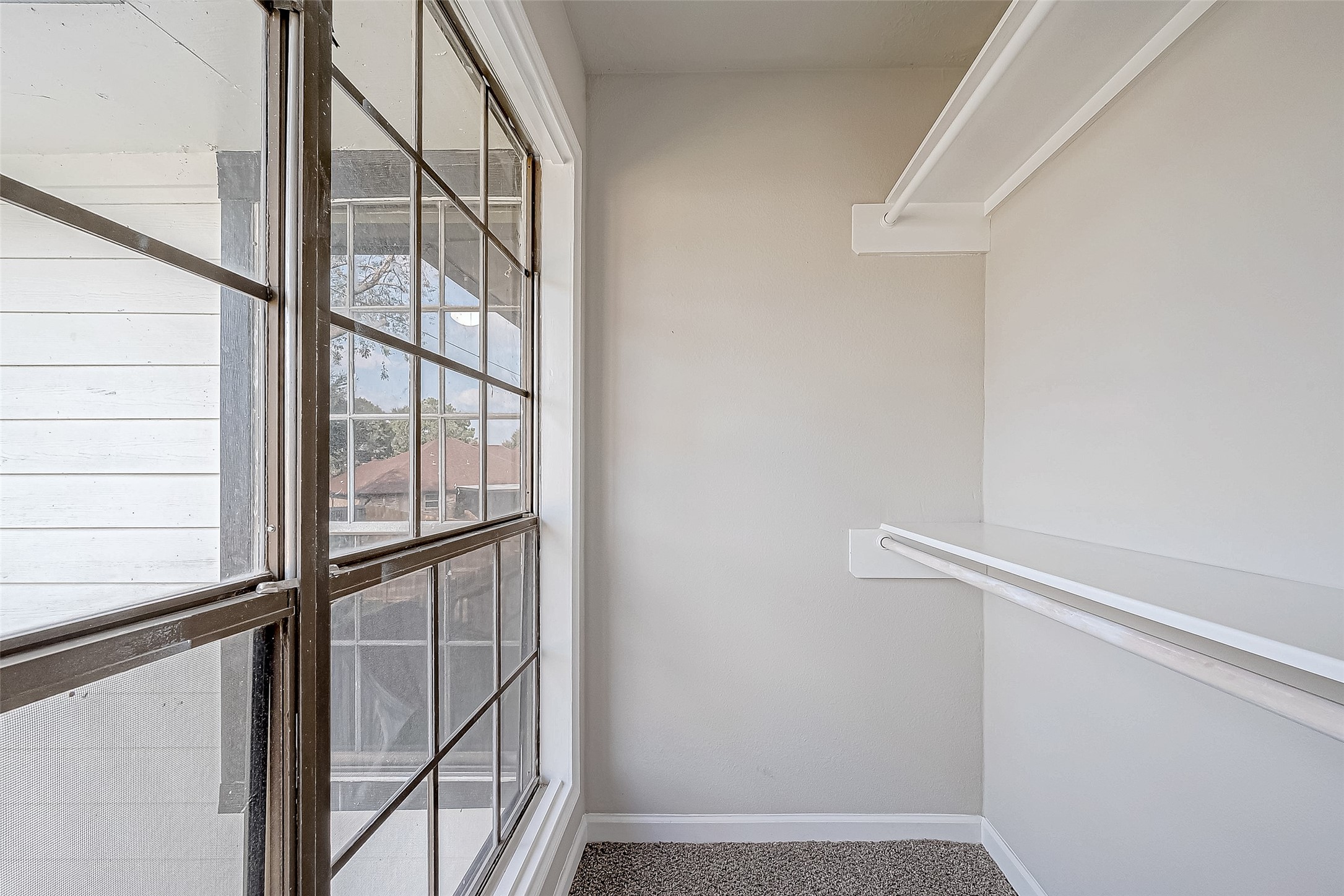 Walk-in closet with large windows and built-in shelves, offering abundant natural light and ample storage.