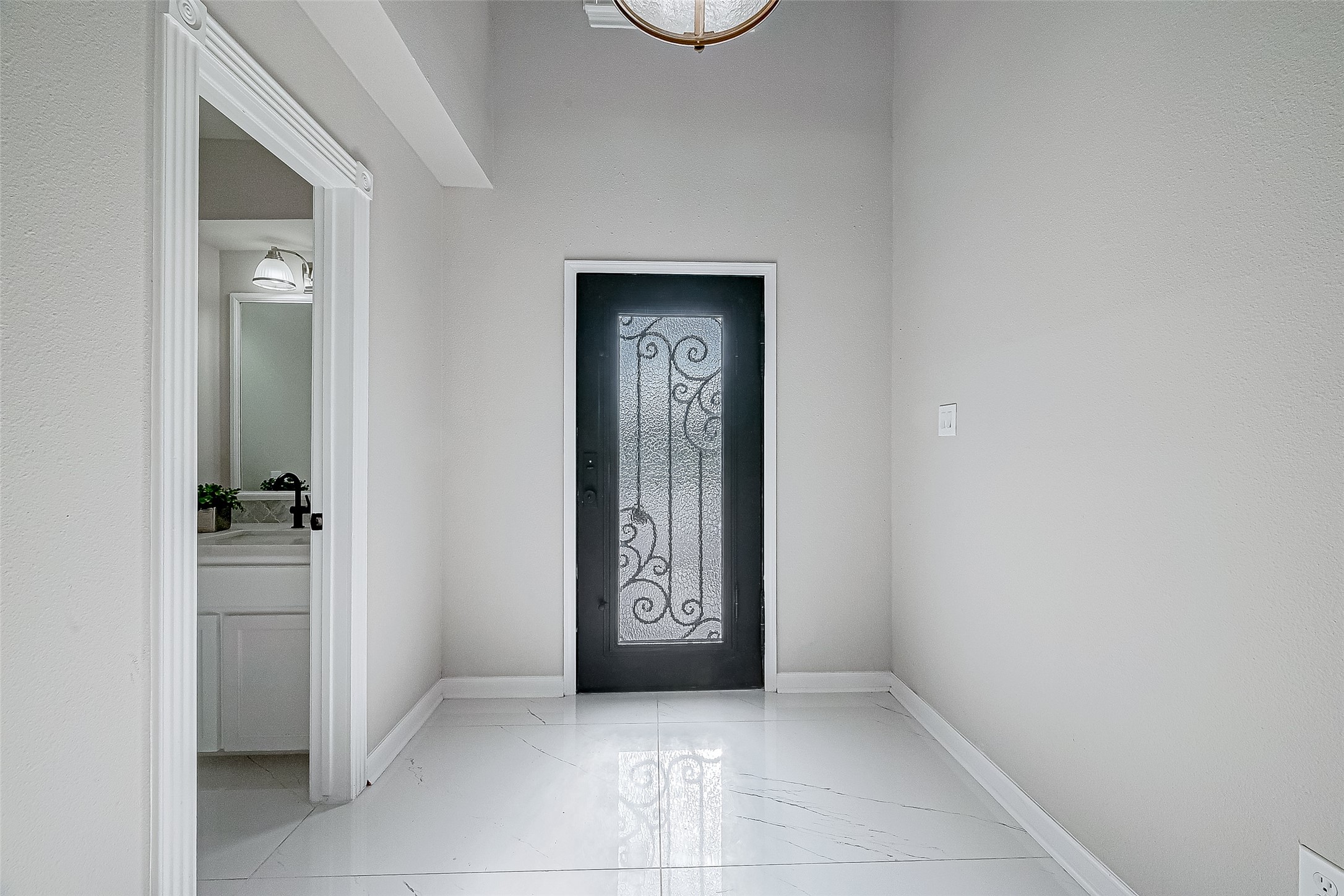 Bright, modern entryway featuring a decorative black door and white tile flooring. Bright, modern entryway featuring a decorative black door and white tile flooring.