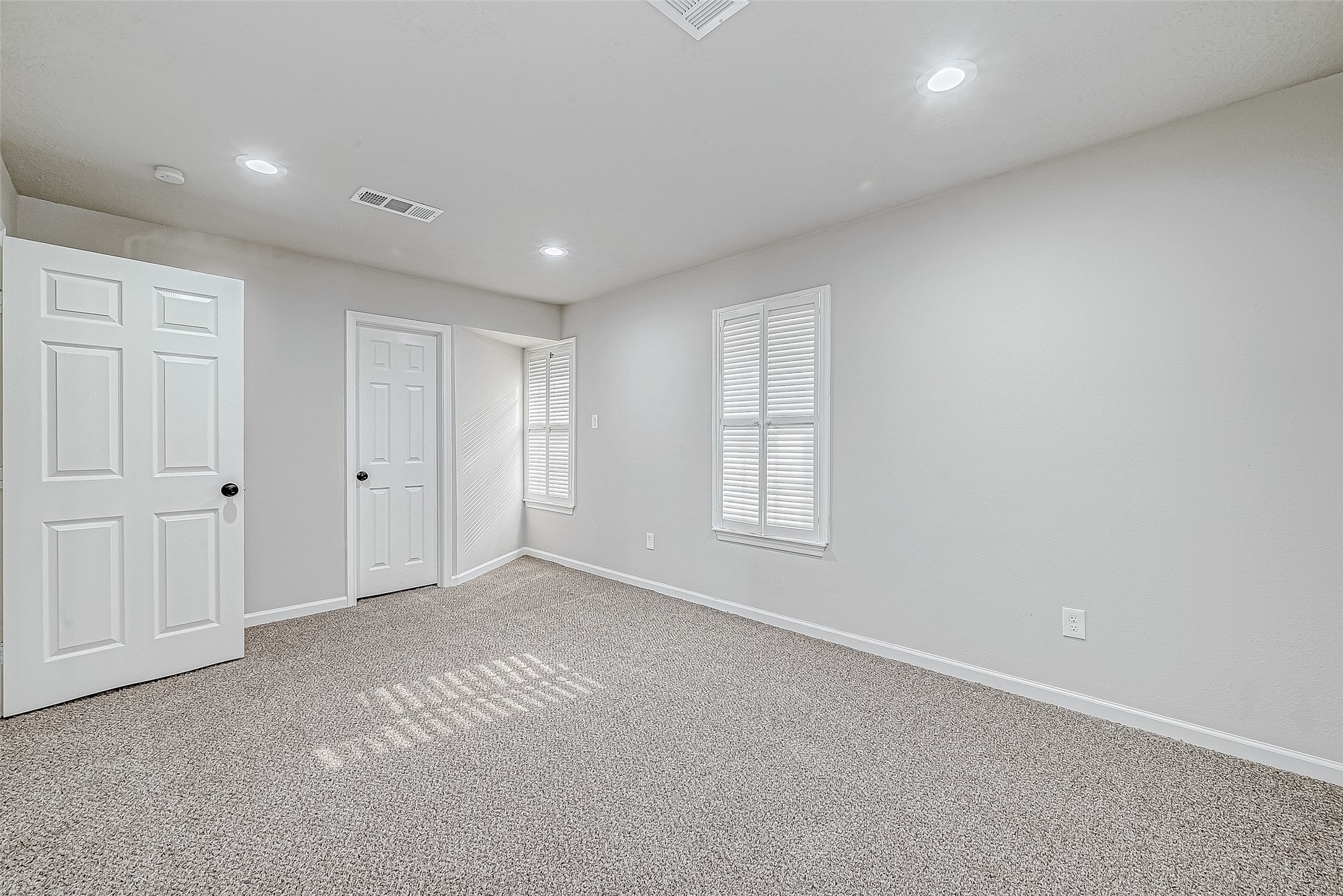 A bright room with neutral walls and carpet flooring, perfect for a bedroom or office.