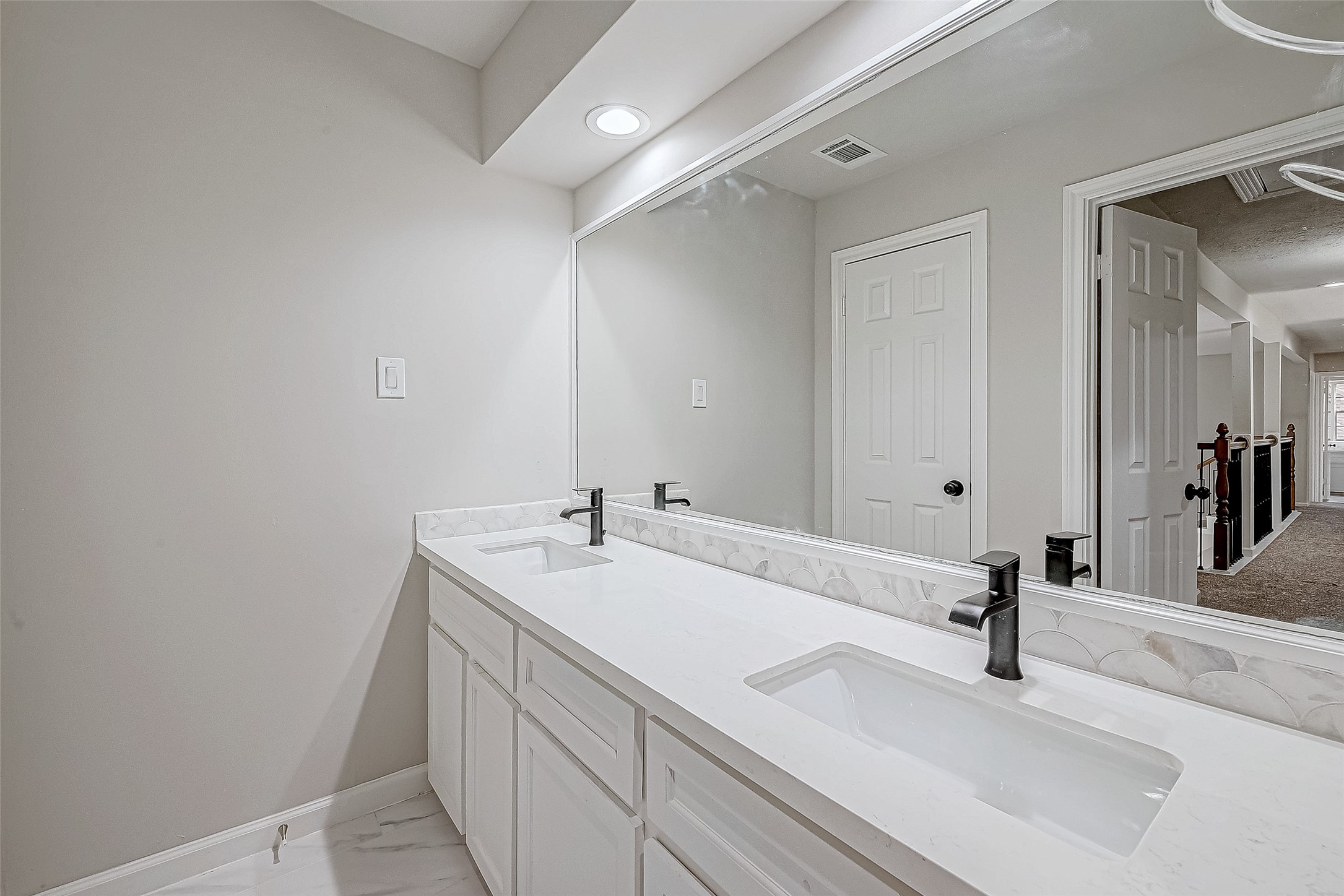 A modern bathroom with a double vanity featuring sleek black faucets and a large mirror.