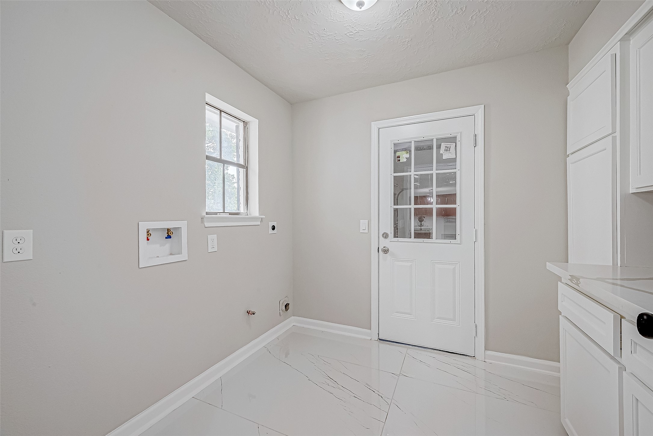 A bright, clean laundry room features a window for natural light and washer/dryer hookups.