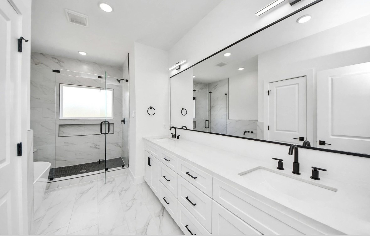 Spacious primary bathroom featuring a shower and tub combination with a clean white design and black accents for a sleek, modern finish. Spacious primary bathroom featuring a shower and tub combination with a clean white design and black accents for a sleek, modern finish.