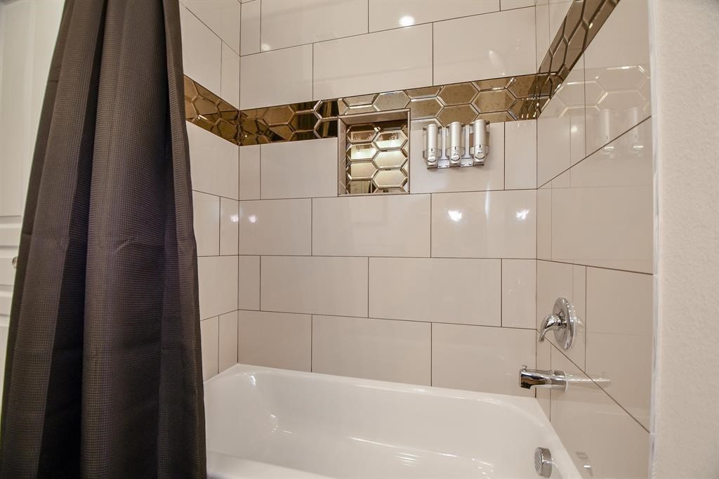 Upstairs Modern bathroom with a sleek bathtub, glossy beige tiles, and stylish hexagonal accent trim.