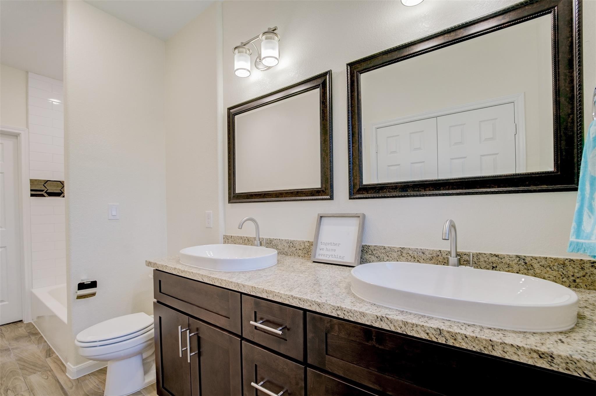 Upstairs bathroom features a dual-sink vanity with granite countertops and framed mirrors. Access to both upstairs bedrooms.