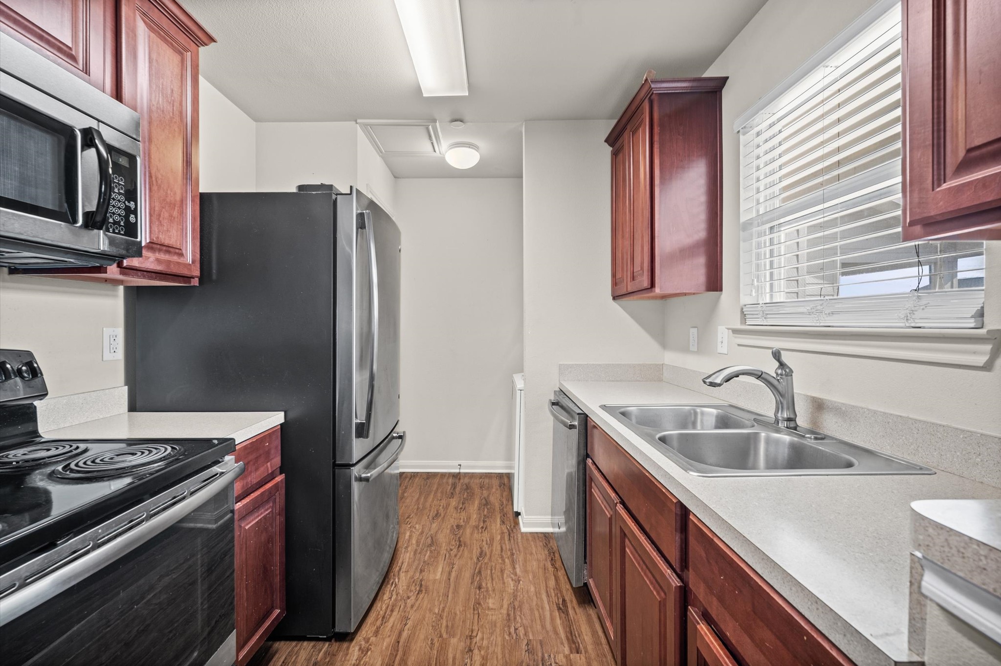 Charming kitchen with rich wood cabinetry, modern stainless steel appliances, and a bright window overlooking the sink, offering a cozy and functional cooking space.