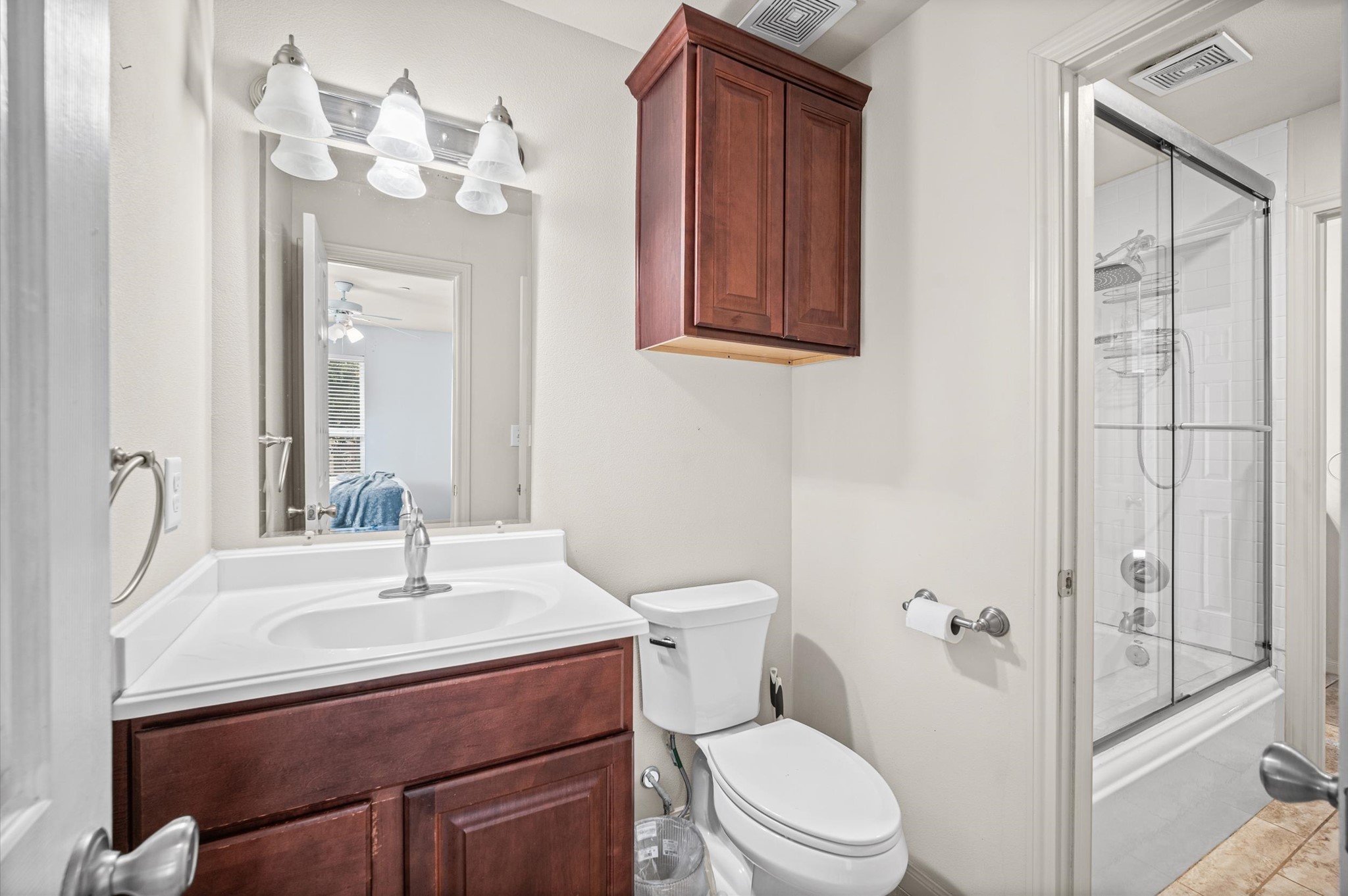 Elegant bathroom featuring a modern vanity with ample cabinet space, sleek lighting, and a glass-enclosed shower for a touch of luxury.