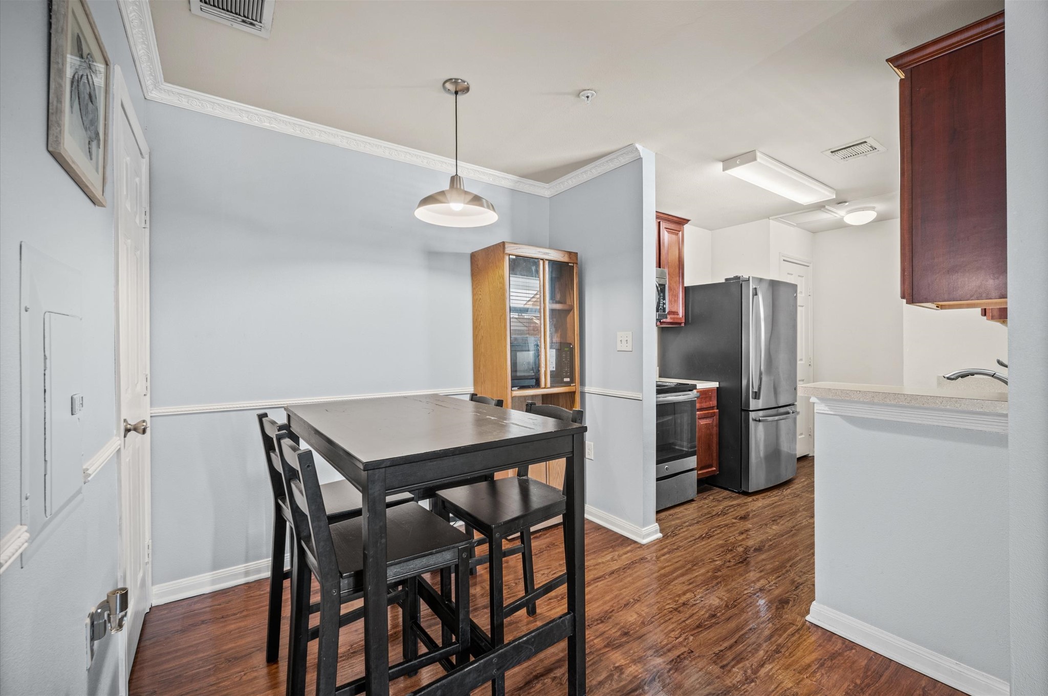Charming kitchen and dining area featuring modern appliances, sleek wood cabinetry, and warm hardwood floors, perfect for cozy meals and gatherings.
