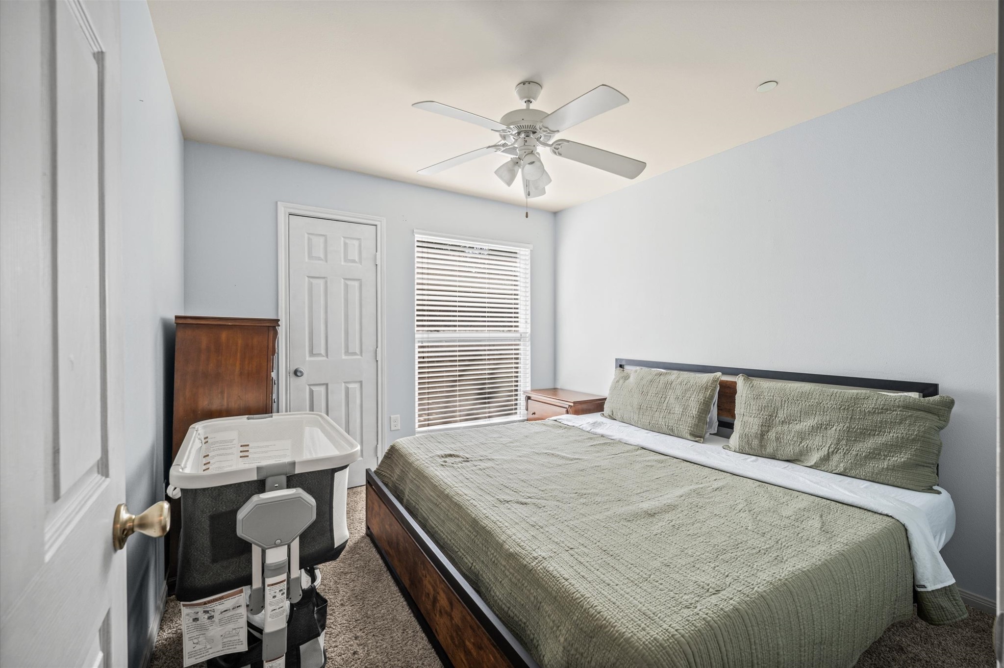 Cozy bedroom, soft carpeting, and ample natural light from large windows.