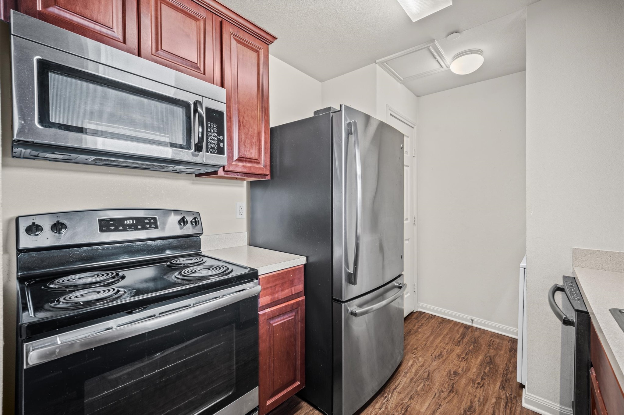 Modern kitchen featuring sleek stainless steel appliances, rich wooden cabinetry, and elegant countertops, all set upon warm wood laminate flooring.