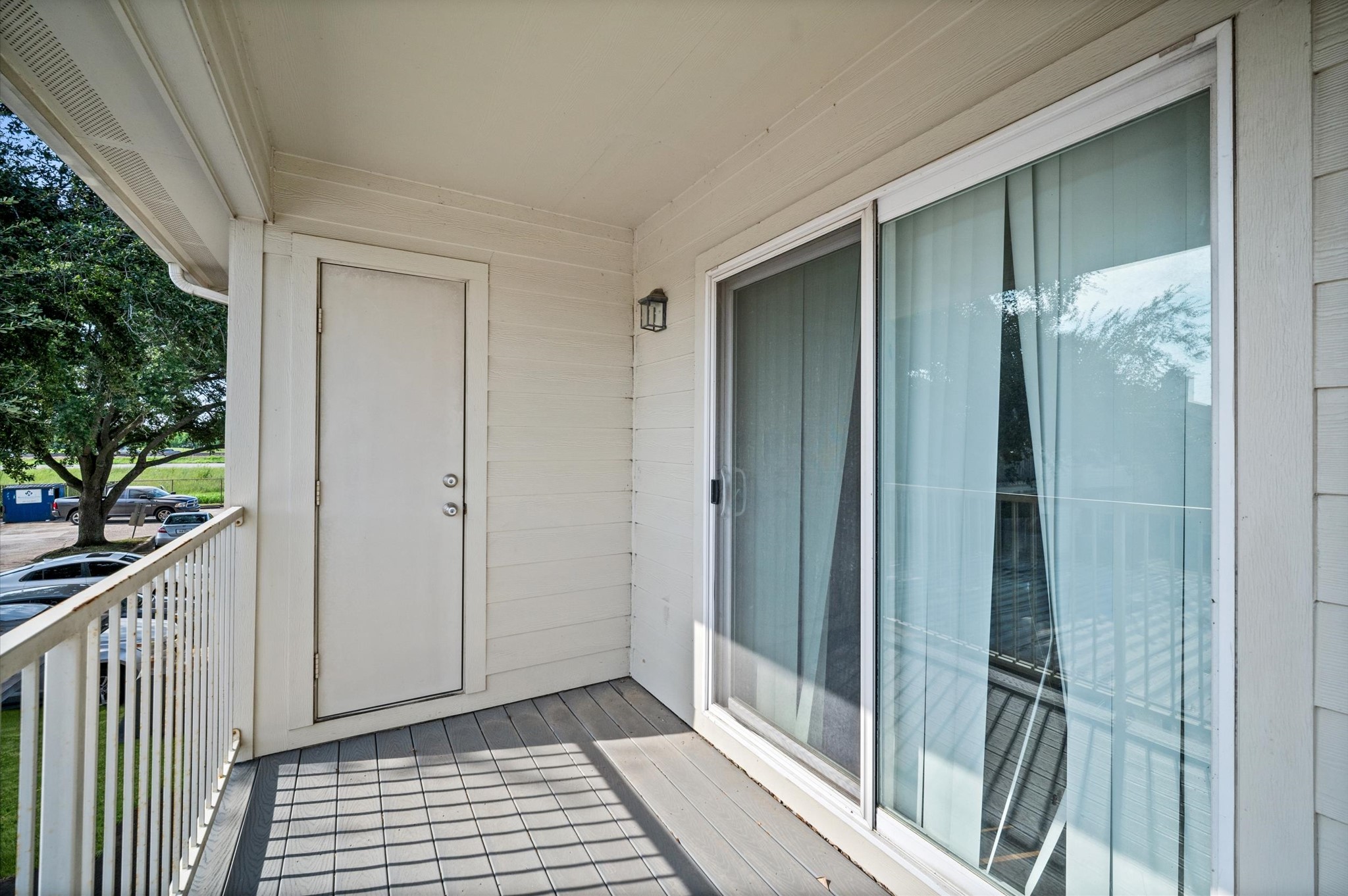Charming balcony with sliding glass doors, offering a cozy outdoor space and a view of lush greenery.