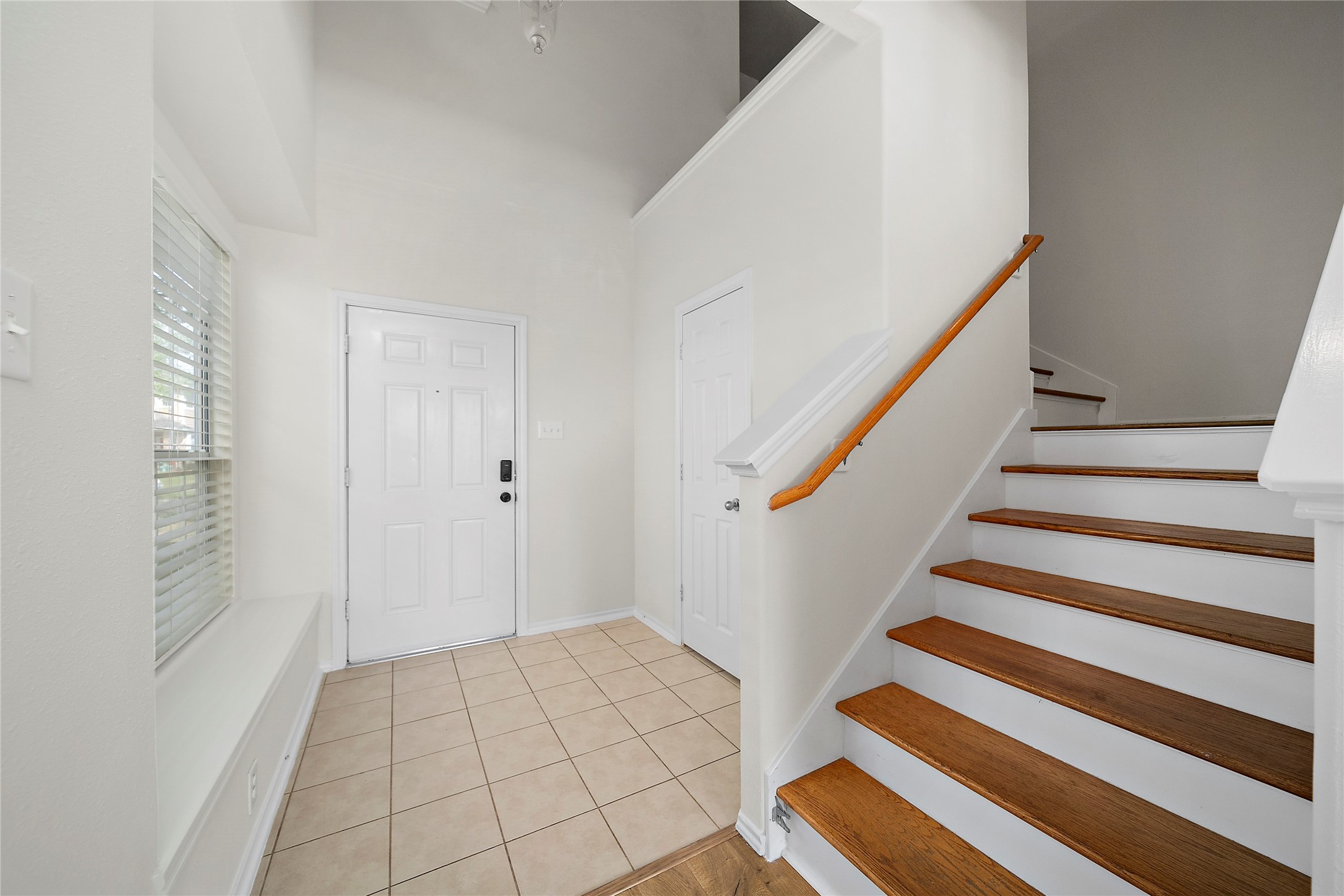 Bright, spacious kitchen with white cabinets, modern appliances, and ample counter space. It opens to a dining area with natural light from large windows, creating a welcoming atmosphere.