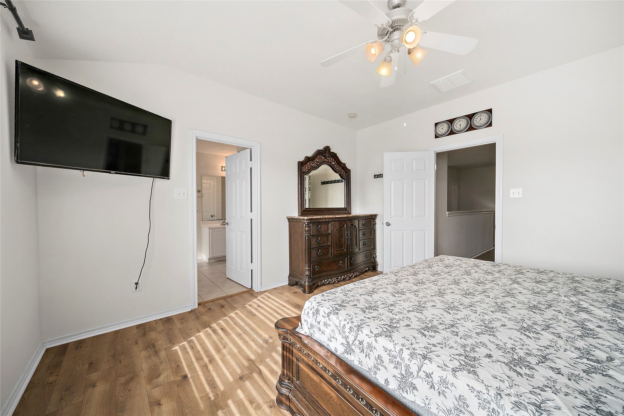 This bright, airy room features large windows, wood flooring, and a ceiling fan. It includes a cozy daybed with storage drawers, a small piano, and a colorful bookshelf, creating a versatile space for relaxation or hobbies.