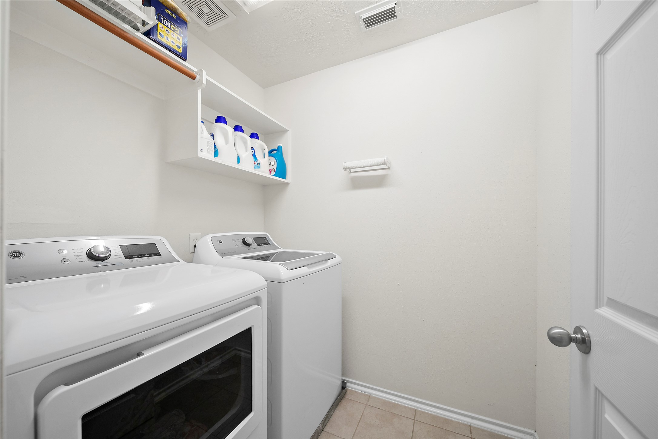 Spacious and efficient laundry room equipped with modern washer and dryer, ample shelving for storage, and easy-to-clean flooring.