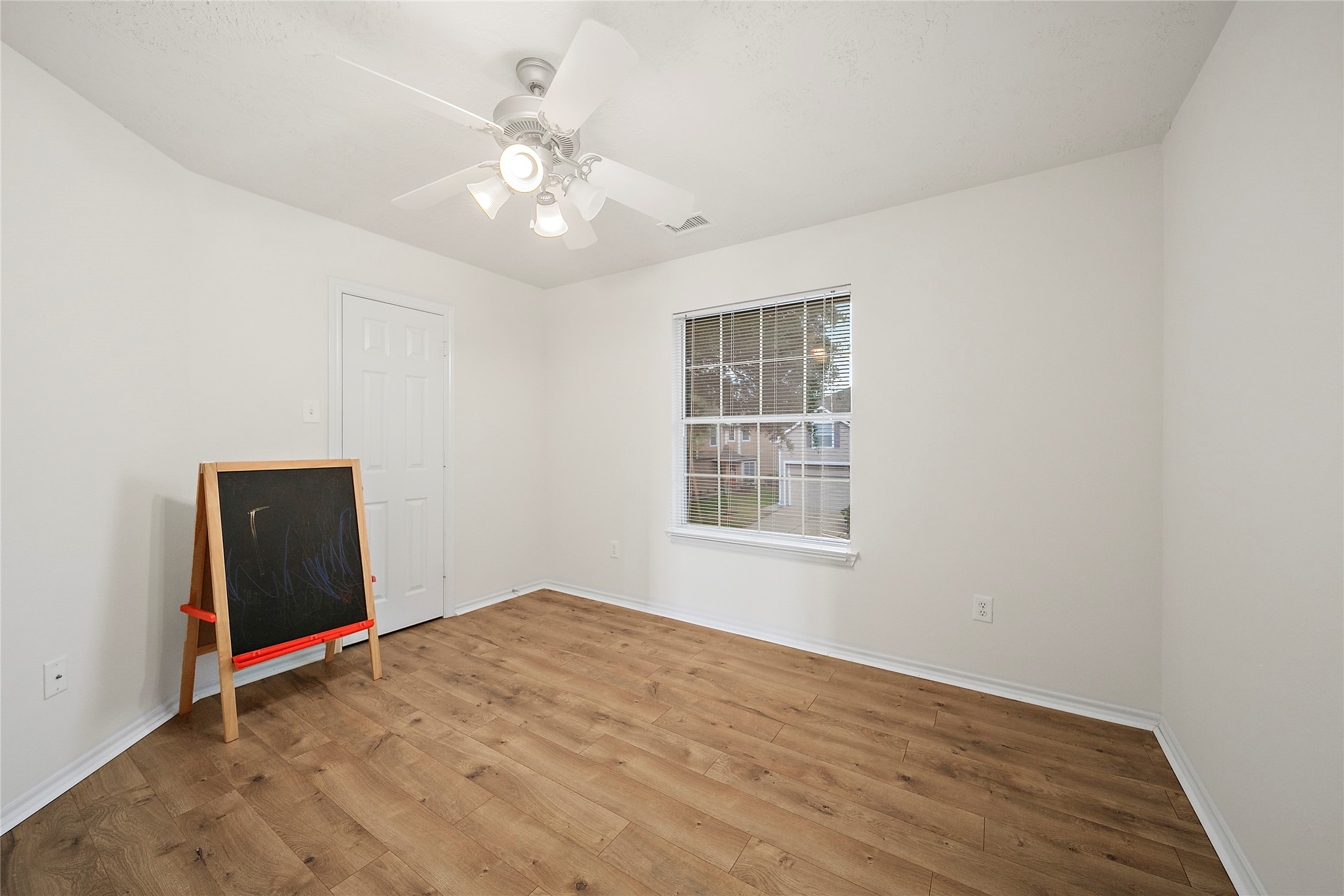Cozy secondary bedroom with natural light, sleek ceiling fan, and elegant wood flooring.