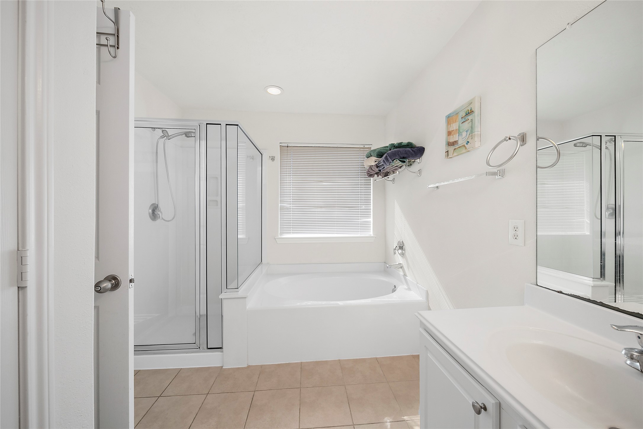 Indulge in relaxation in this inviting primary bath, featuring a spacious soaking tub, a separate glass-enclosed shower, and abundant natural light.