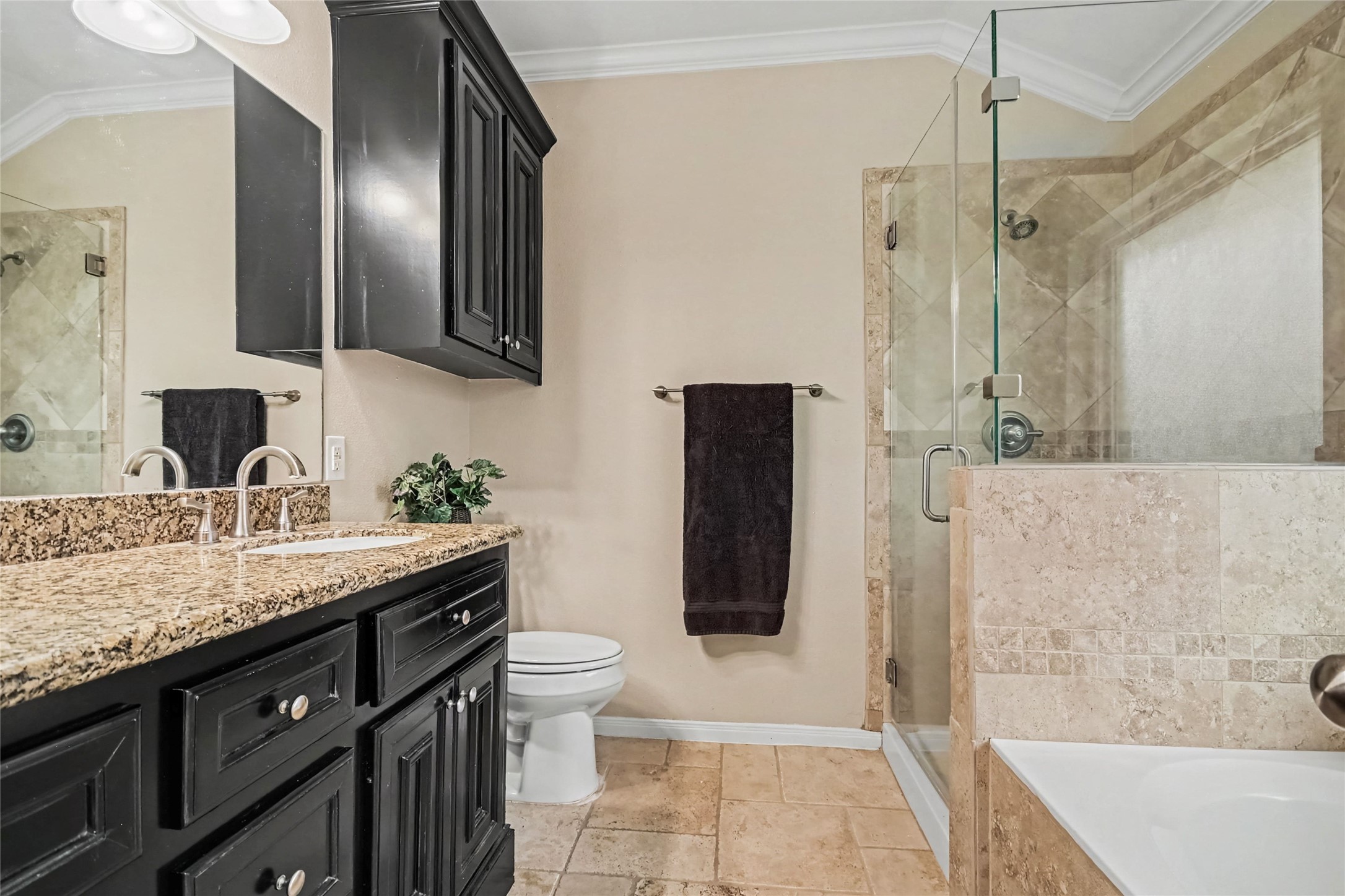Granite double sink vanity with separate soaking tub and separate shower, all surrounded by lovely stone tile, elevated toilet