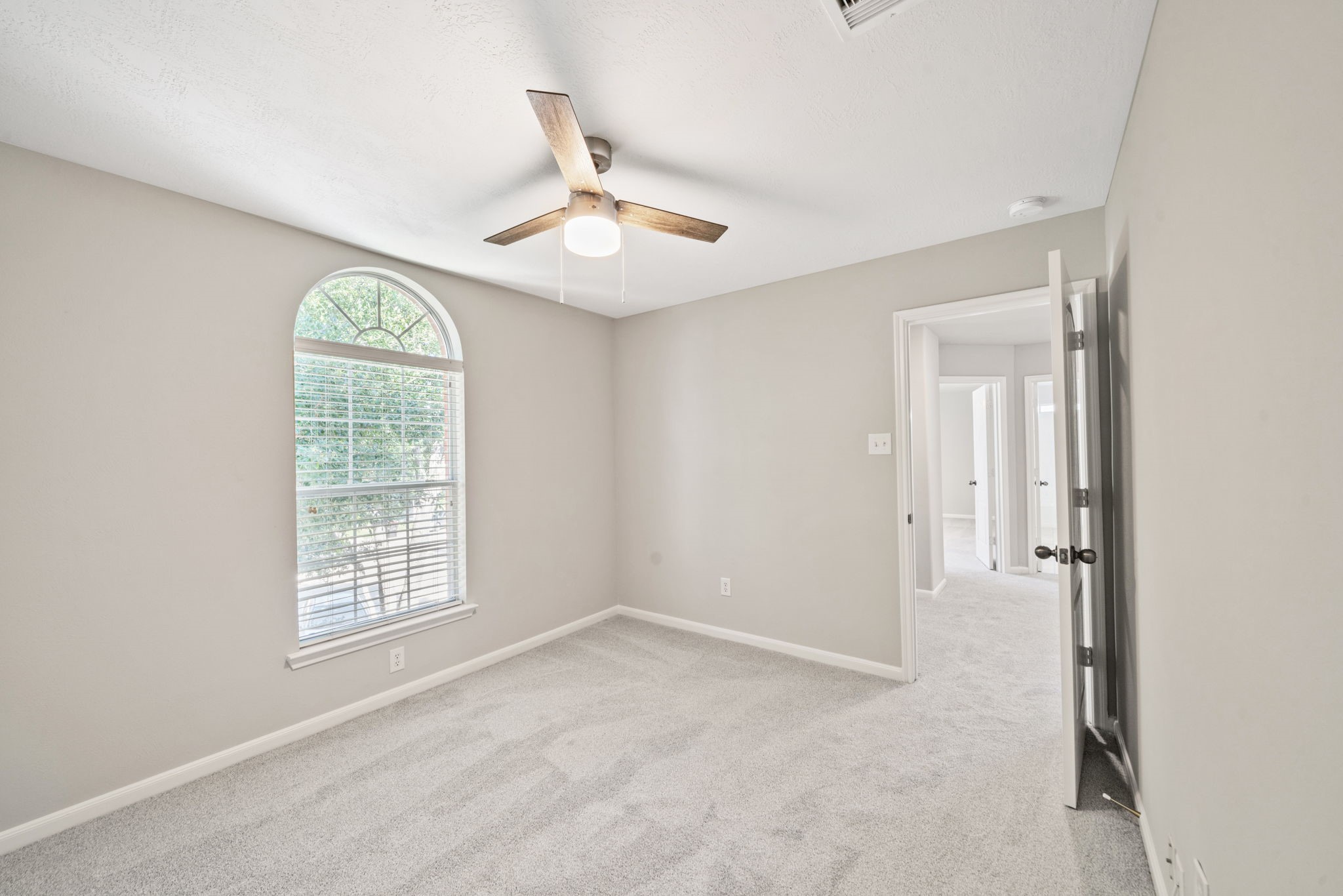 Bright secondary bedroom with ceiling fan and natural light.