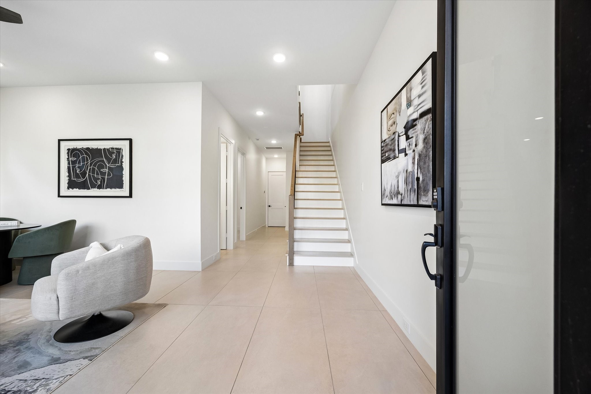 A view looking at the front entrance towards the first floor hallway. Door straight ahead leads to the two car attached garage with epoxy flooring. Door to the end of the hall to the right leads to a closet that is elevator capable, so it provides a large closet (one each floor!). Door down the hallway on the left leads to a guest bedroom with a full bath.