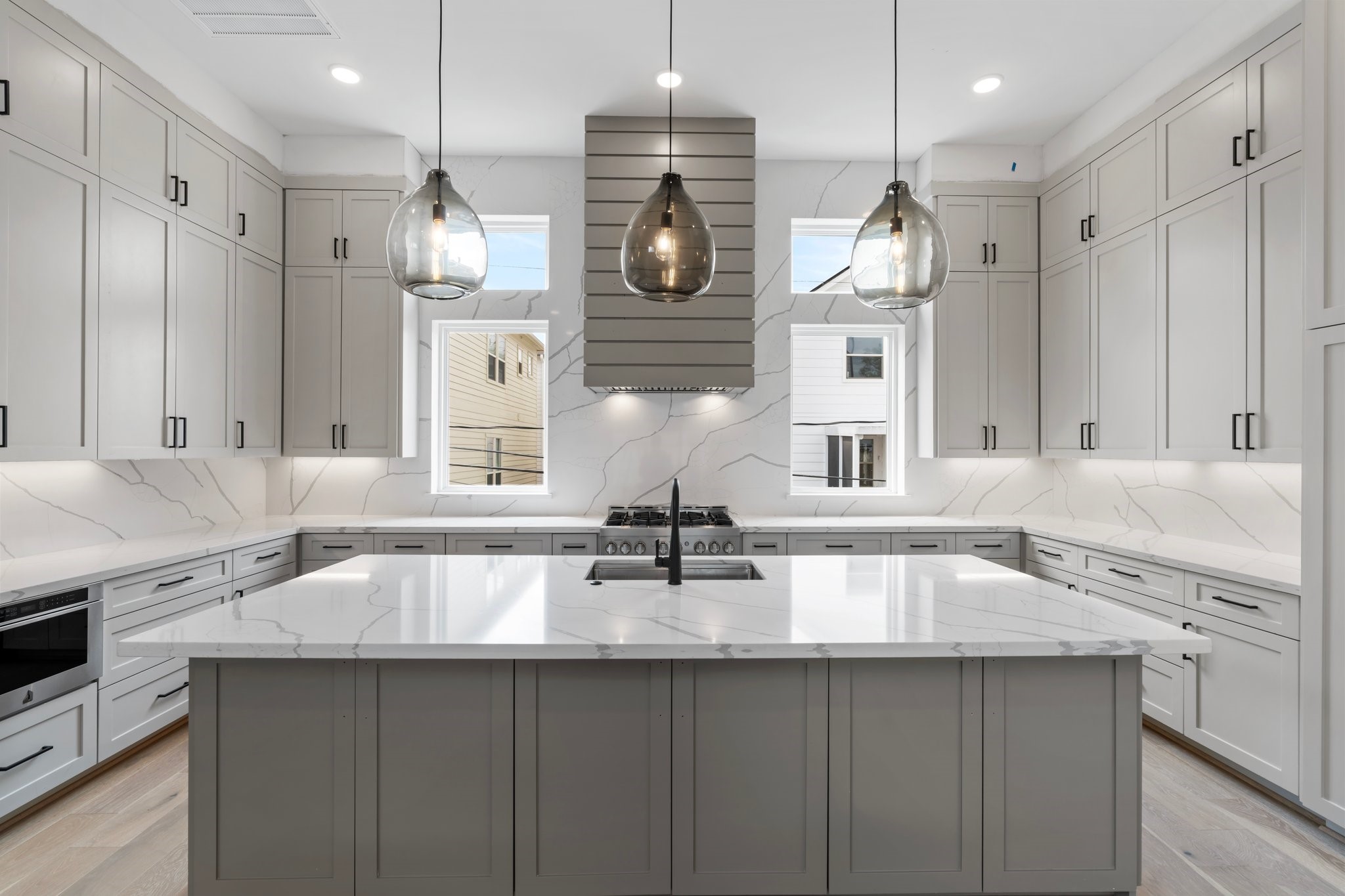 A chefs dream kitchen, perfectly located on the 2nd floor for easy entertaining w/ the main living spaces! Featuring stunning quartz countertops continues up the backsplash. Custom vent hood. Expansive island w/ breakfast bar seating features 3 Visual Comfort Pendant lights above.