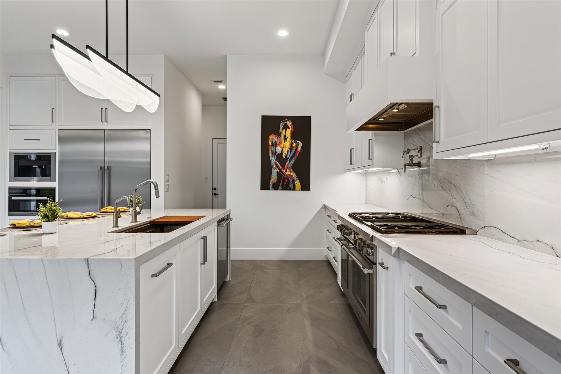 The hallway just beyond the kitchen leads to the walk-in pantry, the designer powder room, a coat closet and the garage entry.