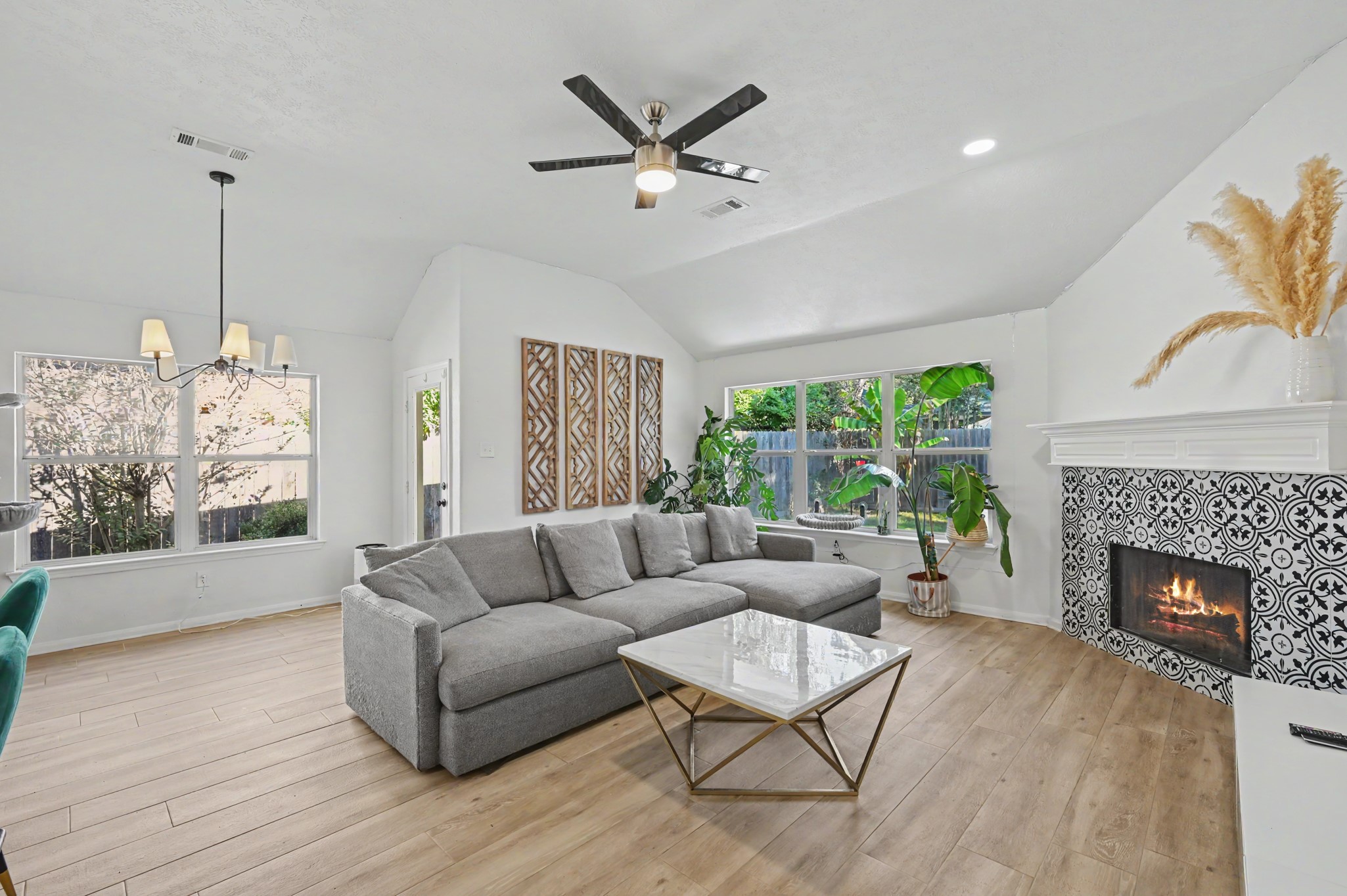 Open living area with fireplace, tile surround, and natural light from large windows