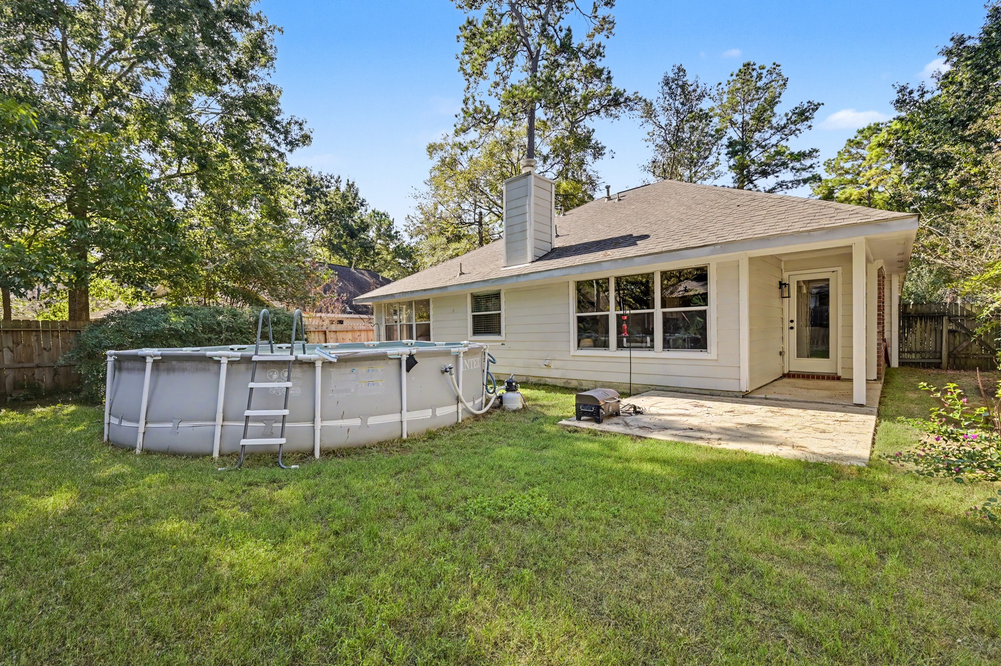 Backyard with covered patio perfect for outdoor gatherings, complemented by a convenient above-ground pool.