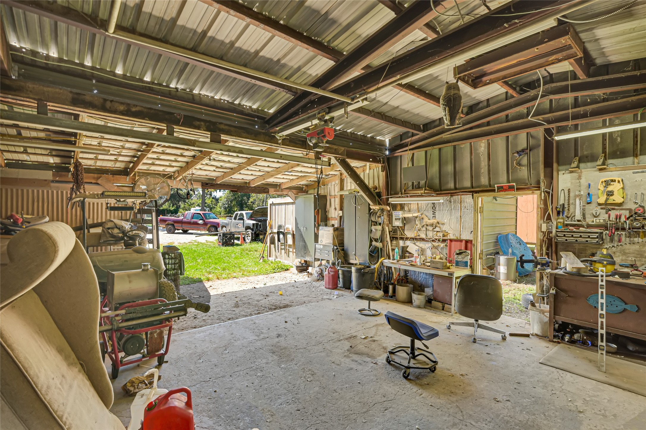 Spacious workshop with ample natural light, featuring a metal roof, workbench, and plenty of storage space for tools and equipment.
