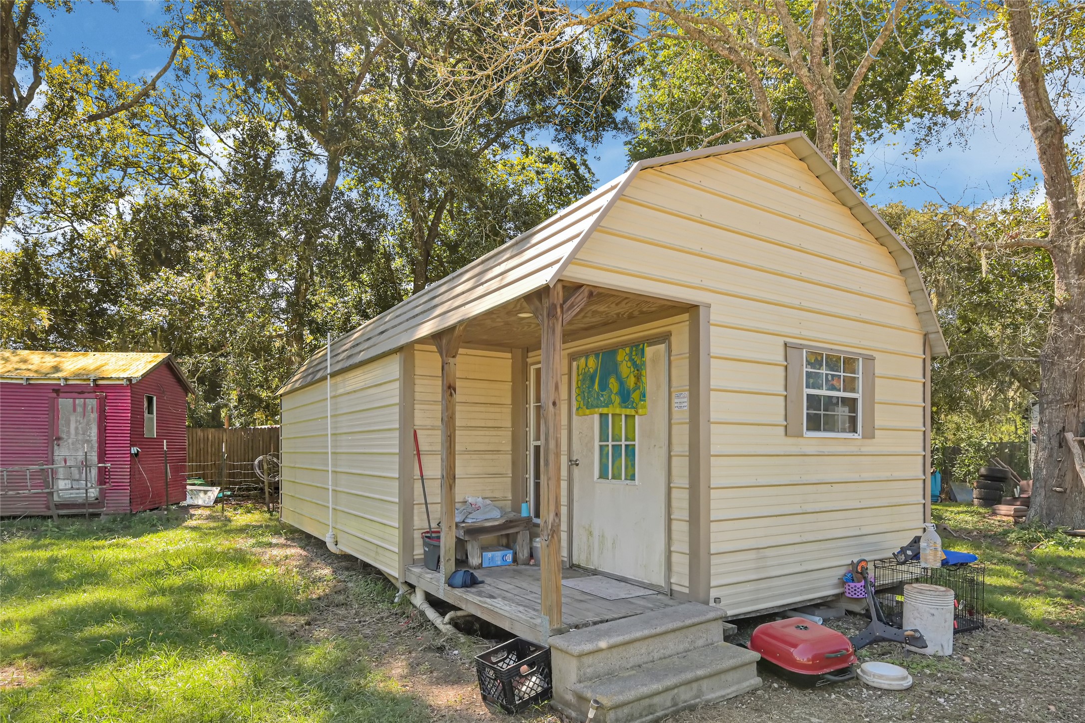 Charming backyard retreat featuring a cozy shed with a welcoming porch, nestled amidst lush greenery, perfect for storage or a personal getaway.
