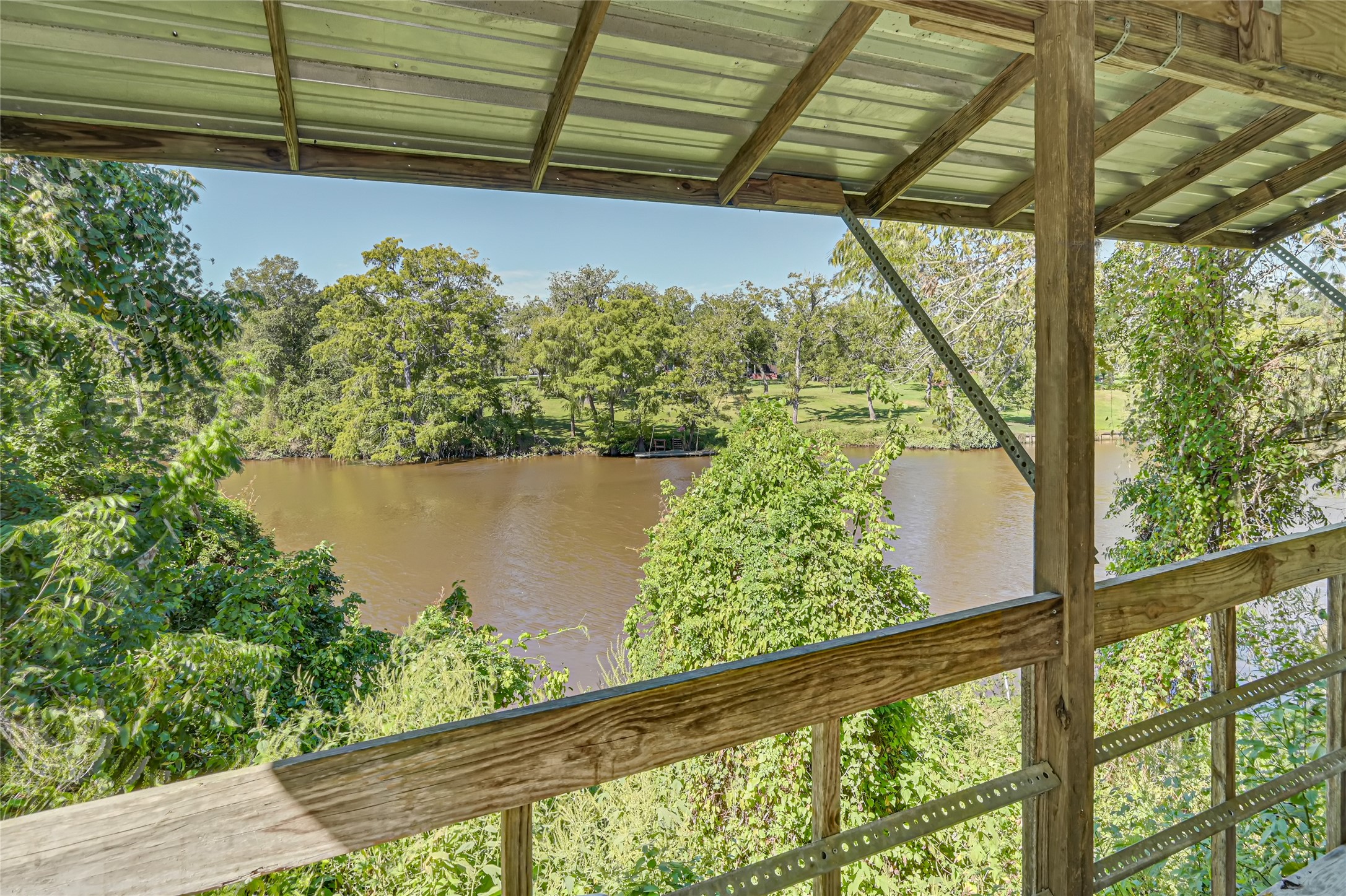 Enjoy serene river views from this charming covered balcony, surrounded by lush greenery for a perfect nature retreat.