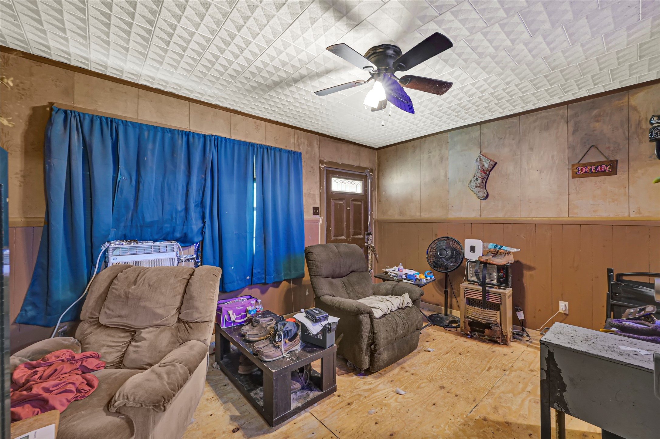 Cozy living space featuring wood-paneled walls, a ceiling fan, and plush armchairs, offering a warm and inviting atmosphere.