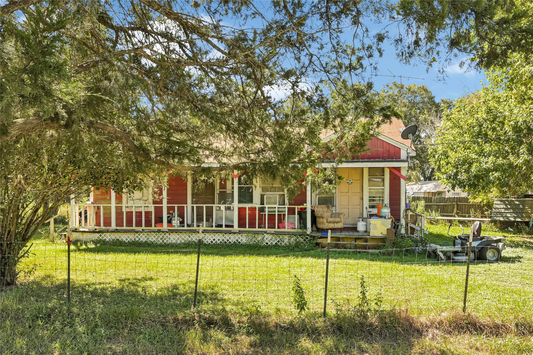 Charming rustic home with a welcoming front porch, surrounded by lush greenery, offering a serene country feel.