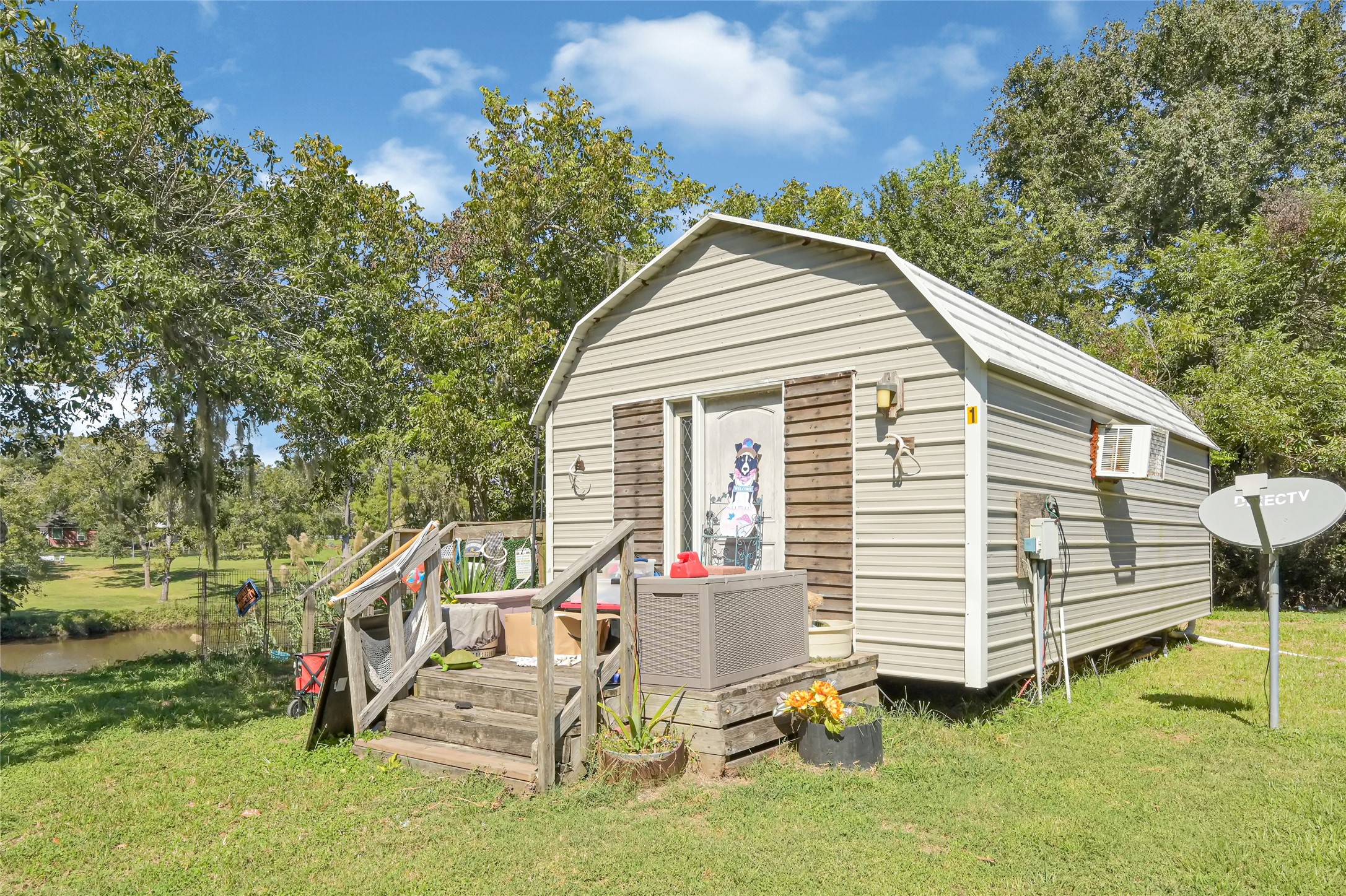 Charming small cabin nestled in lush greenery, offering a cozy retreat with a picturesque view of a nearby stream.